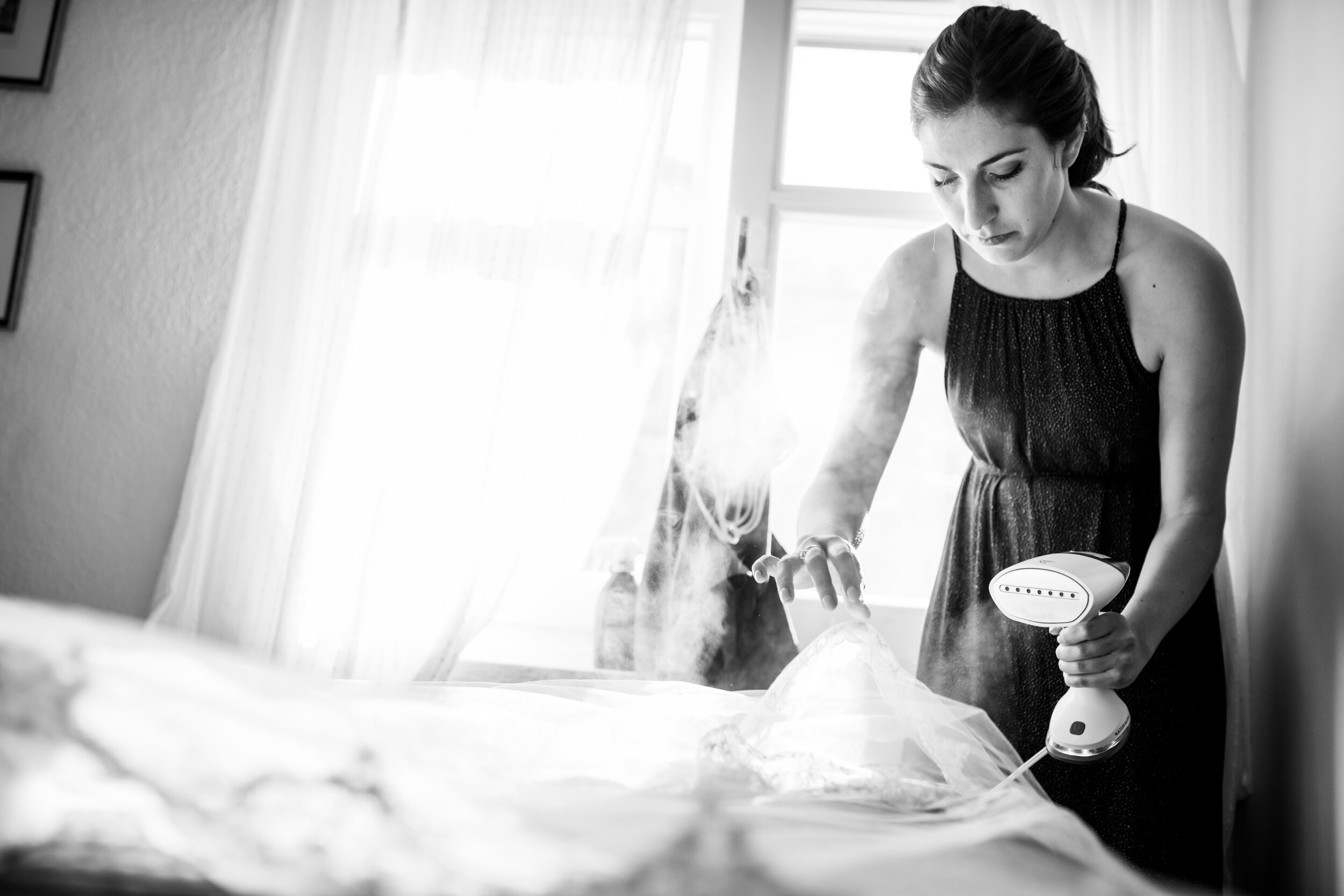 Sister of the bride steam irons the veil: destination wedding photo at the Lost Unicorn Hotel, Tsagarada, Greece by J. Brown Photography.