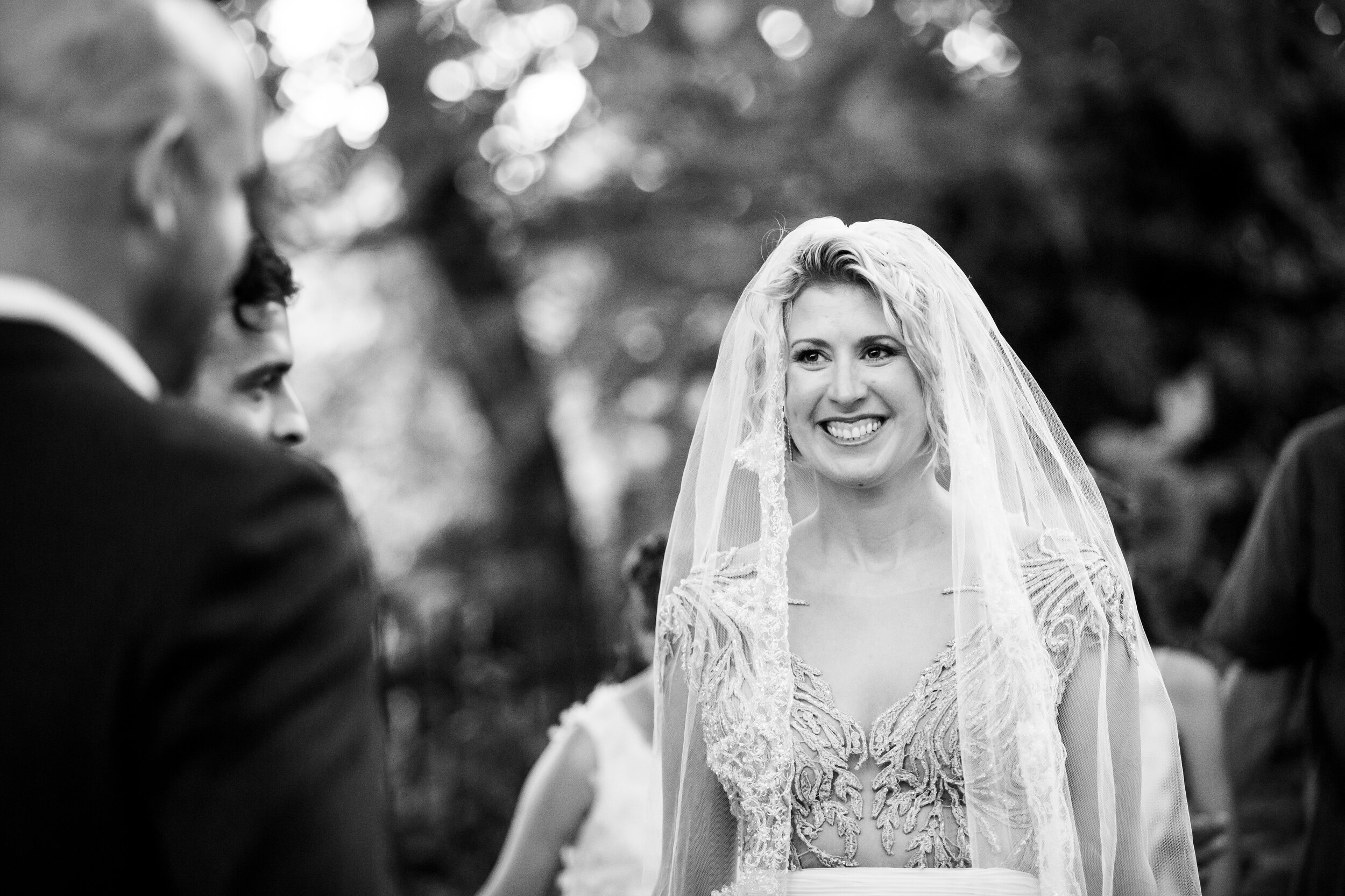 Bride smiles at her groom during the ceremony:  destination wedding photo at the Lost Unicorn Hotel, Tsagarada, Greece by J. Brown Photography.