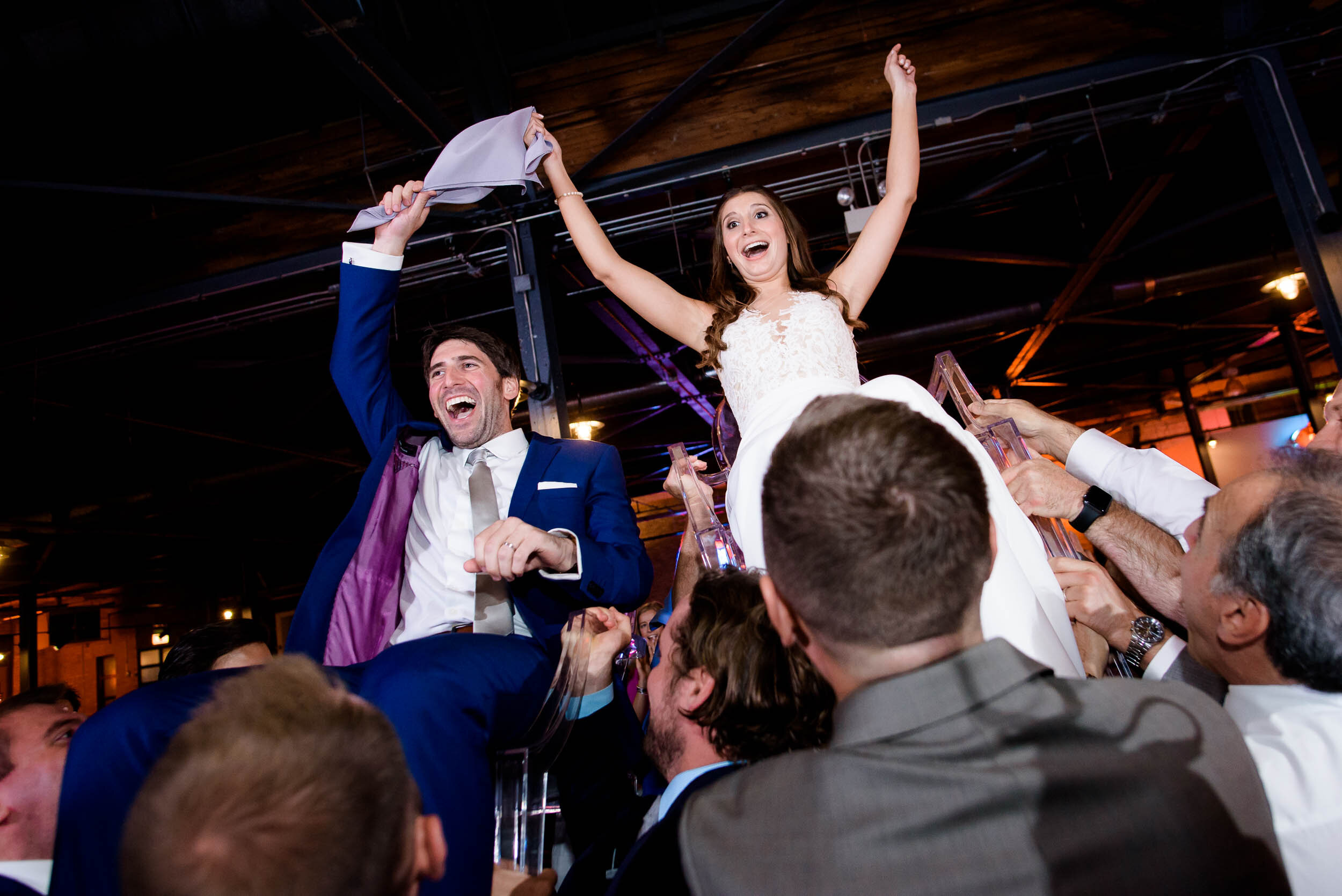 Bride and groom get lifted on chairs during the horah: Ravenswood Event Center Chicago wedding captured by J. Brown Photography.  