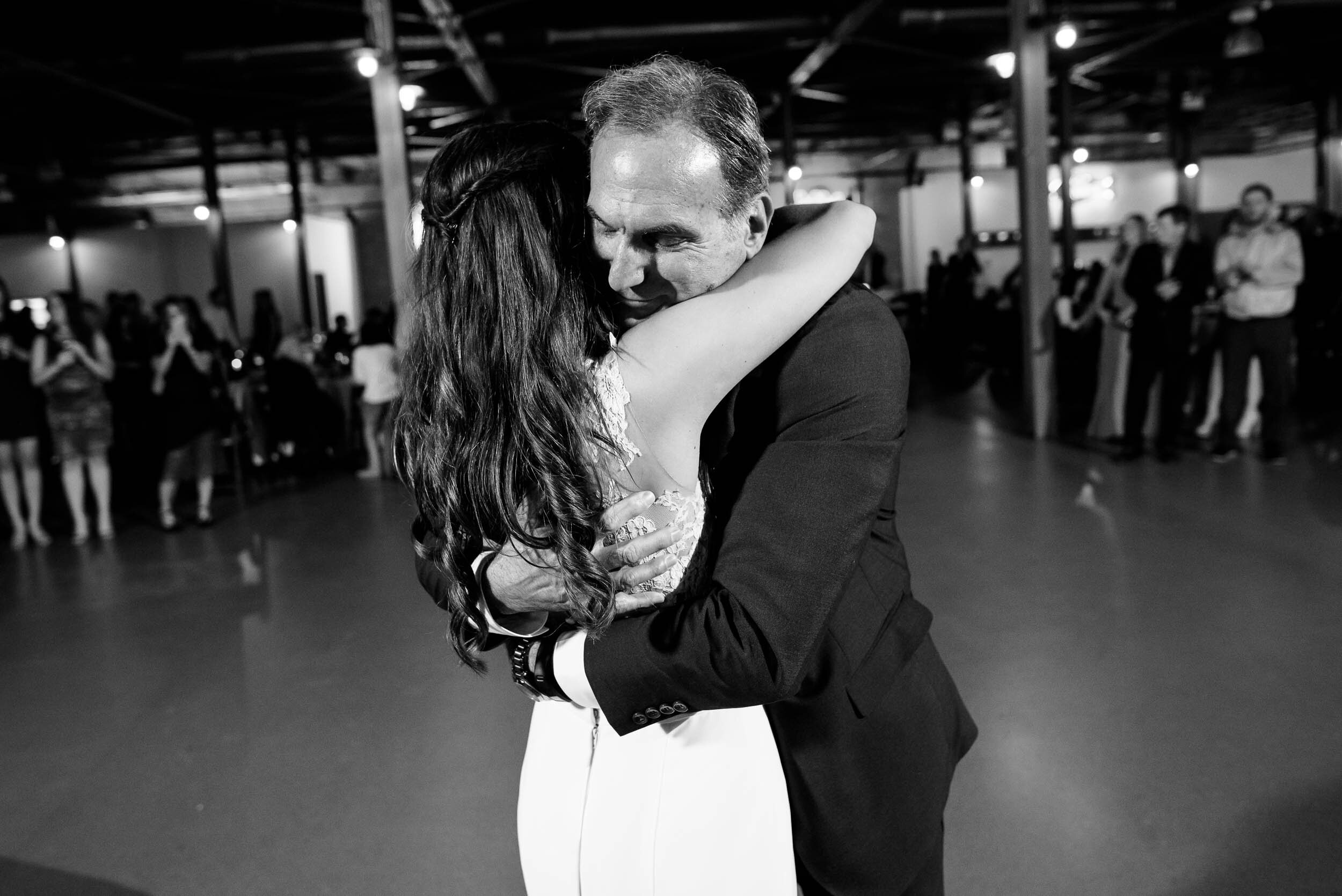 Father hugs the bride during the reception: Ravenswood Event Center Chicago wedding captured by J. Brown Photography.  