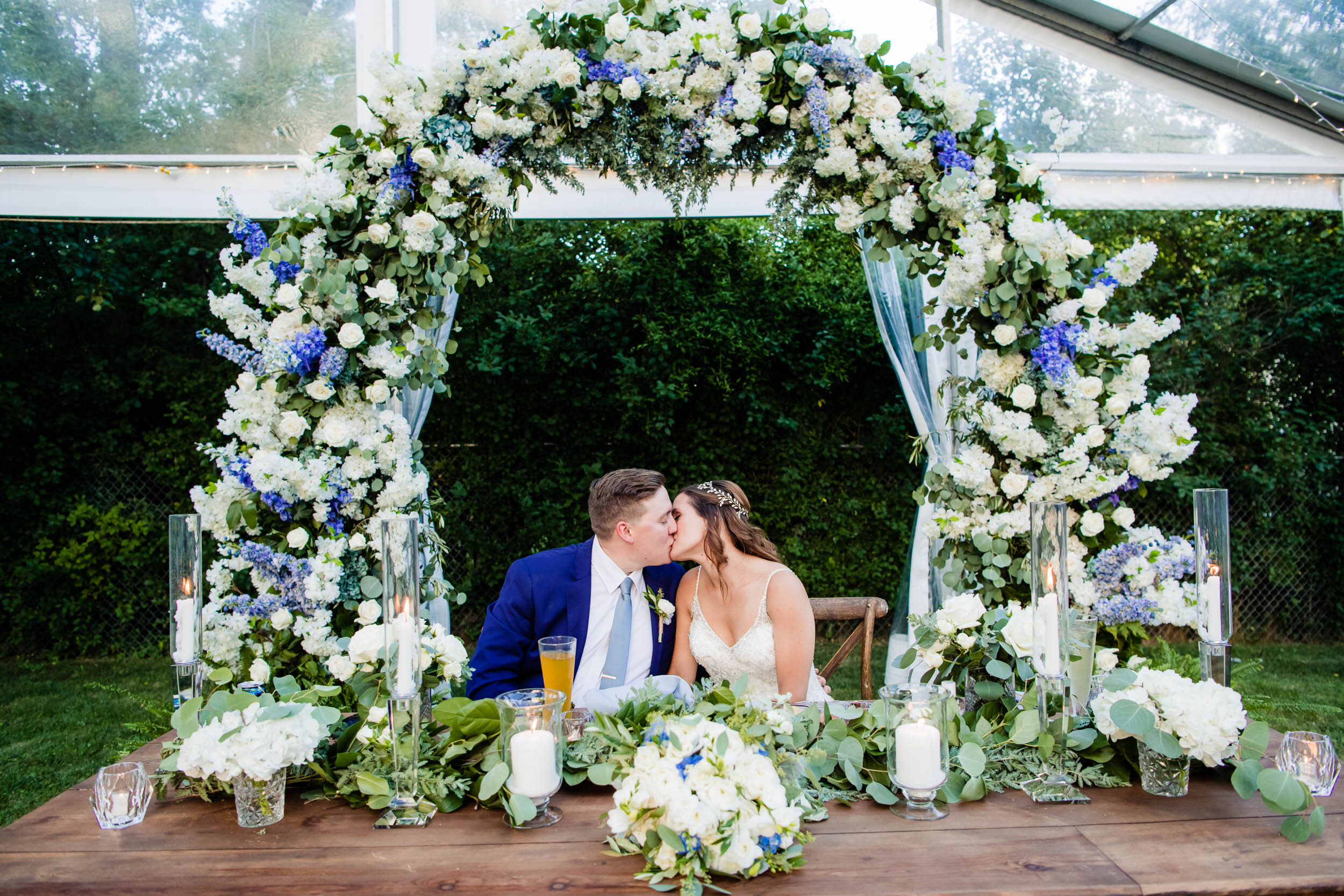 Bride and groom kiss at the headtable:  Chicago backyard wedding photographed by J. Brown Photography.