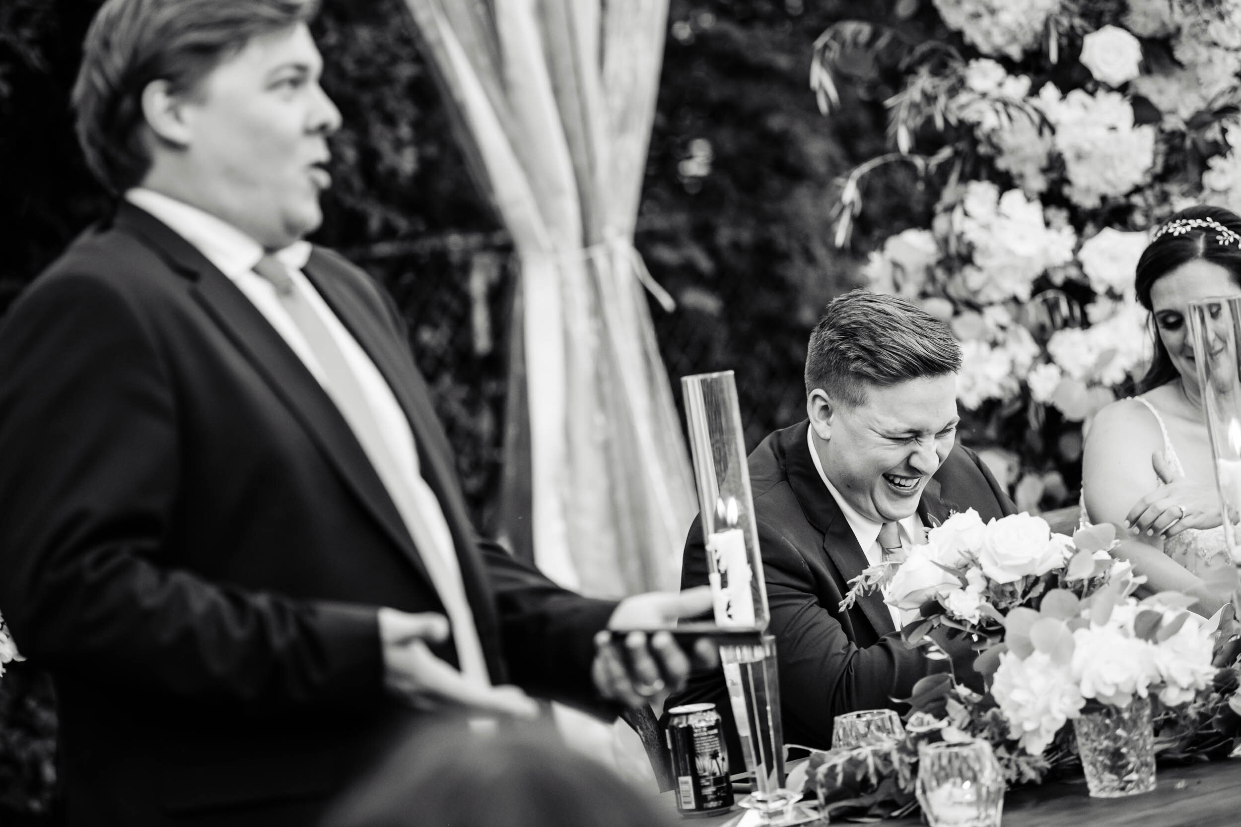 Groom laughs during the best man toast:  Chicago backyard wedding photographed by J. Brown Photography.
