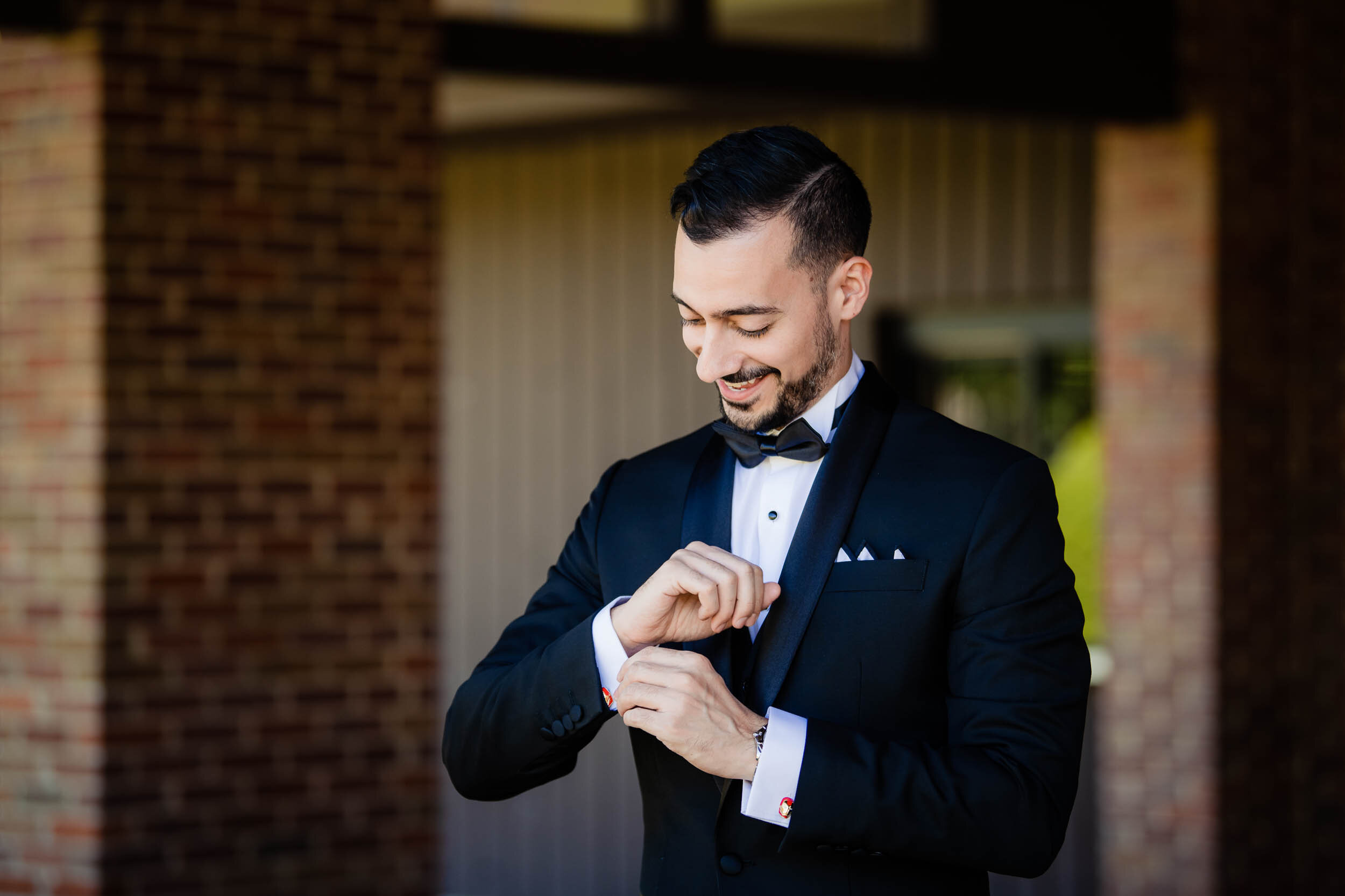 Groom adjusts his Ironman cufflinks:  Chicago wedding photography by J. Brown Photography.