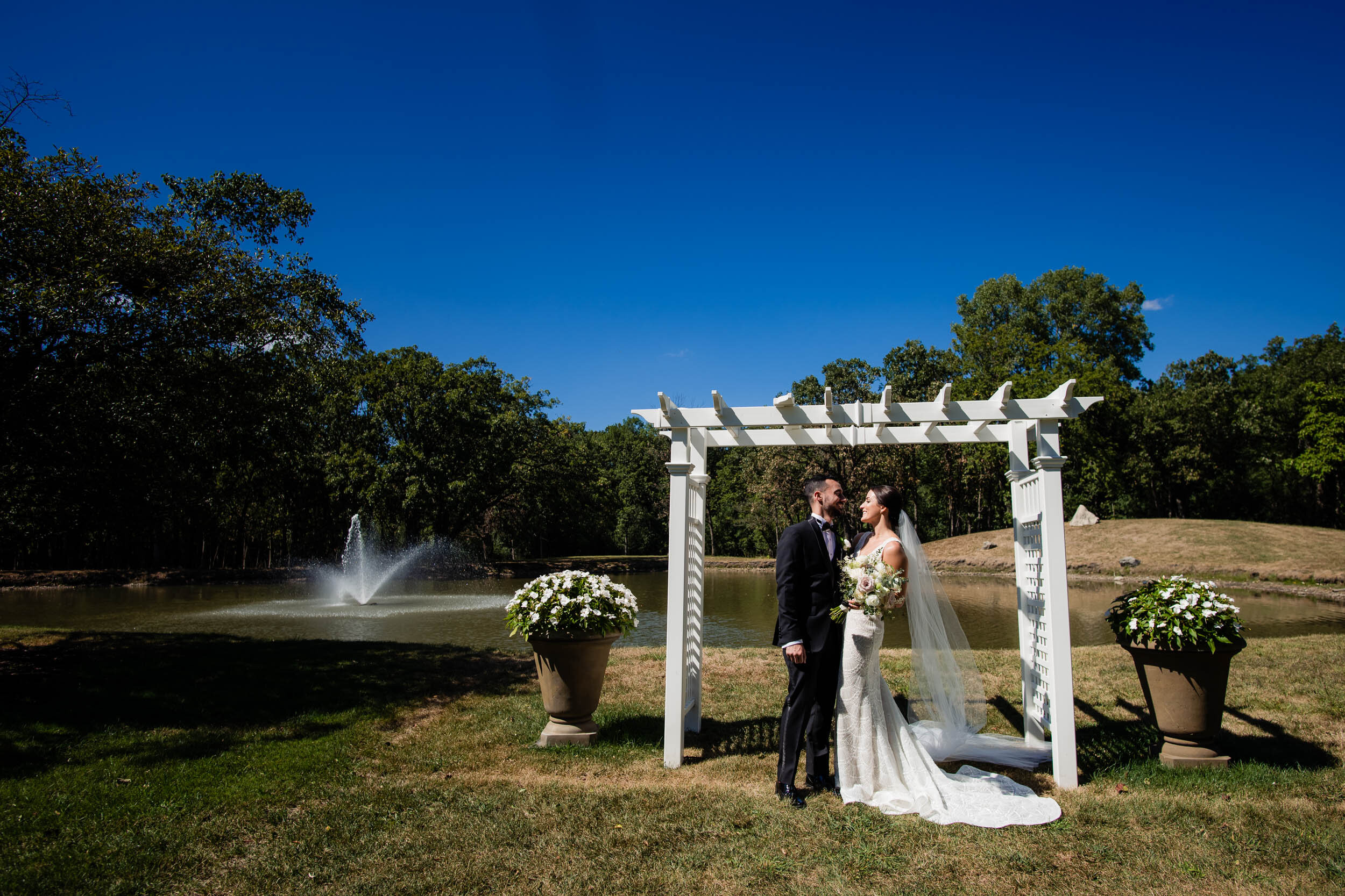 Couple kisses near the pond at the Oakbrook Bath &amp; Tennis Club:  Chicago wedding photography by J. Brown Photography.
