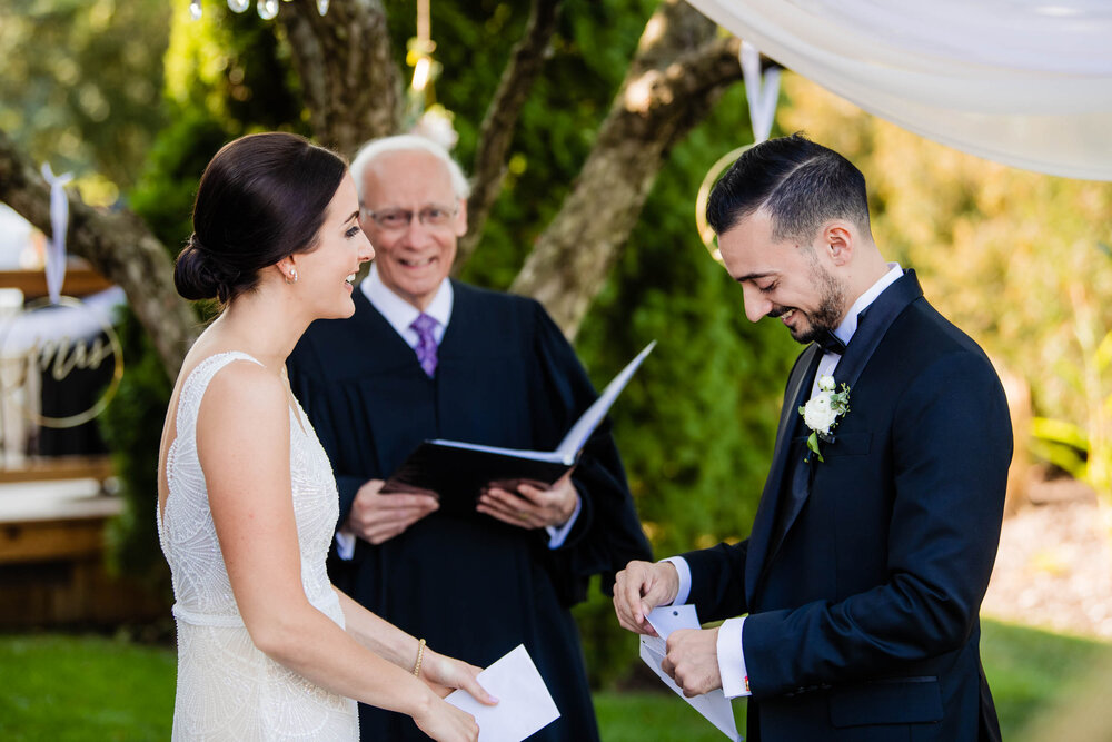 Groom laughs during the bride's vows:  Chicago wedding photography by J. Brown Photography.