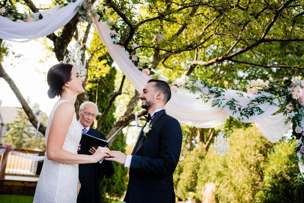 The couple shares a laugh during their backyard wedding ceremony:  Chicago wedding photography by J. Brown Photography.