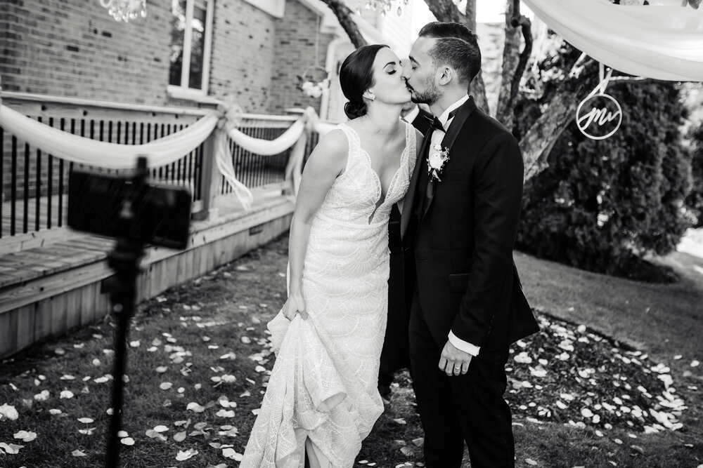 Bride and groom kiss for their guests on Zoom livestream:  Chicago wedding photography by J. Brown Photography.