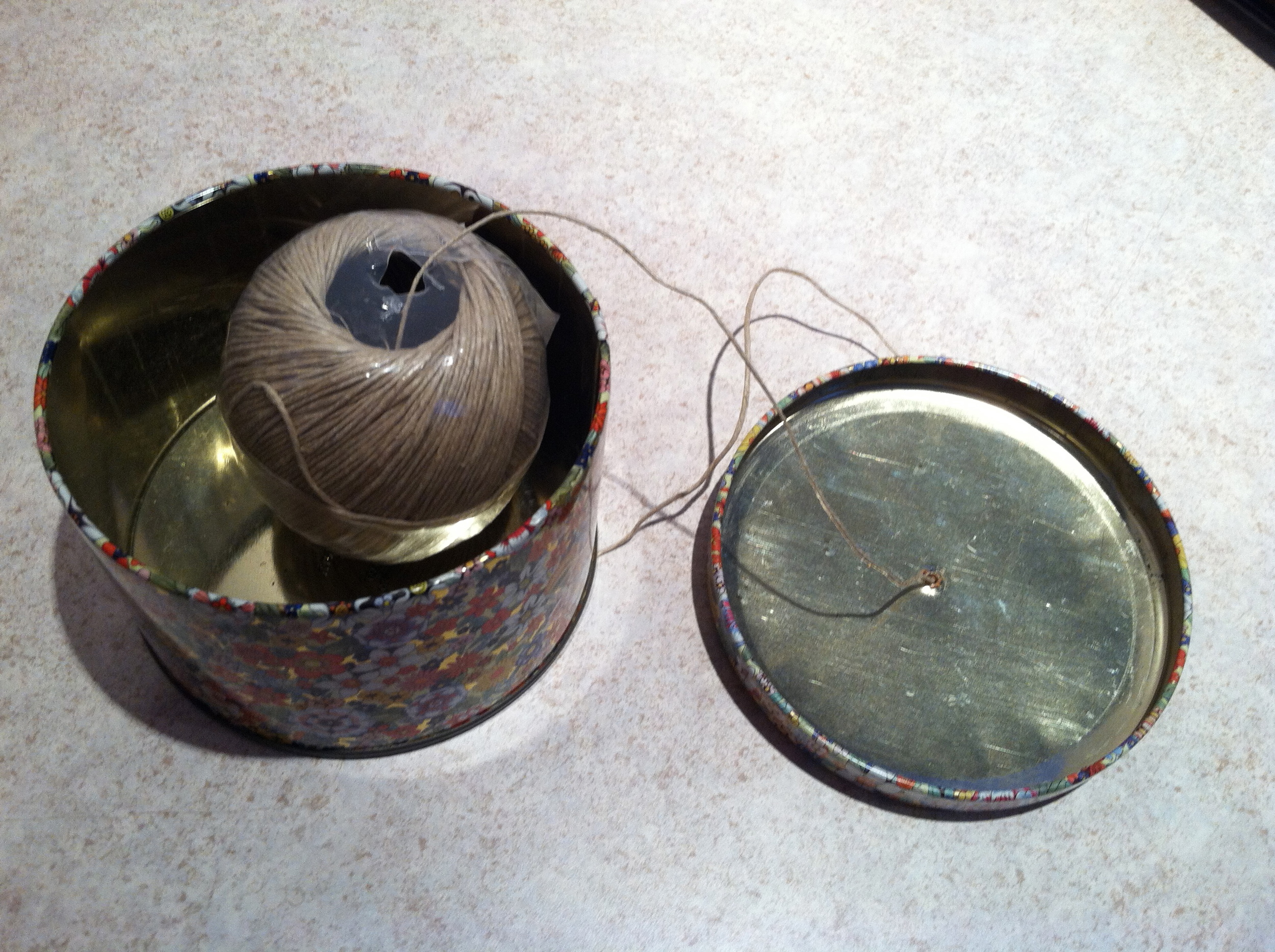  I took a simple tin (purchased for $0.50 at Agape) and punched a hole in the lid. &nbsp;The ball of twine fits perfectly. 