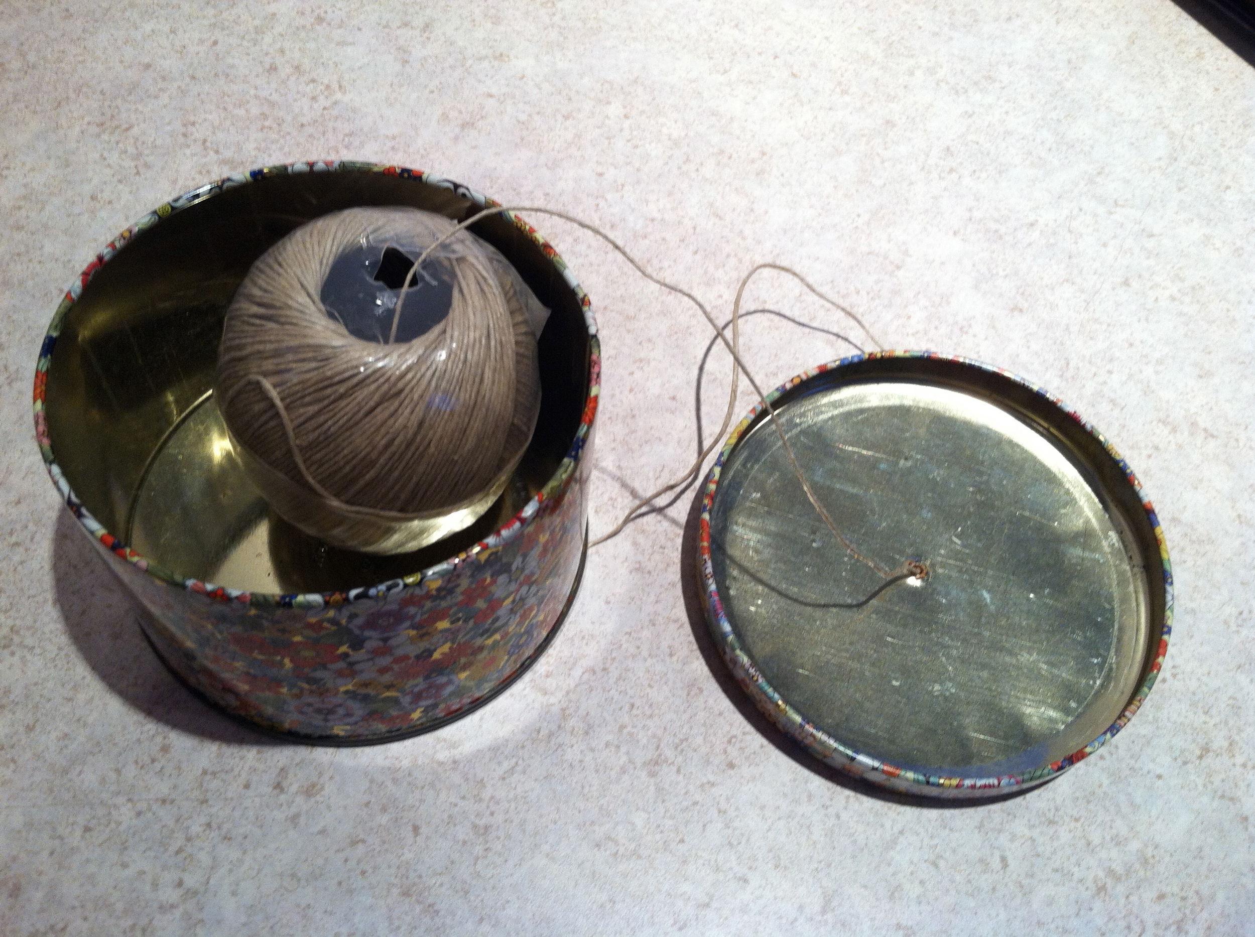 I took a simple tin (purchased for $0.50 at Agape) and punched a hole in the lid. The ball of twine fits perfectly.
