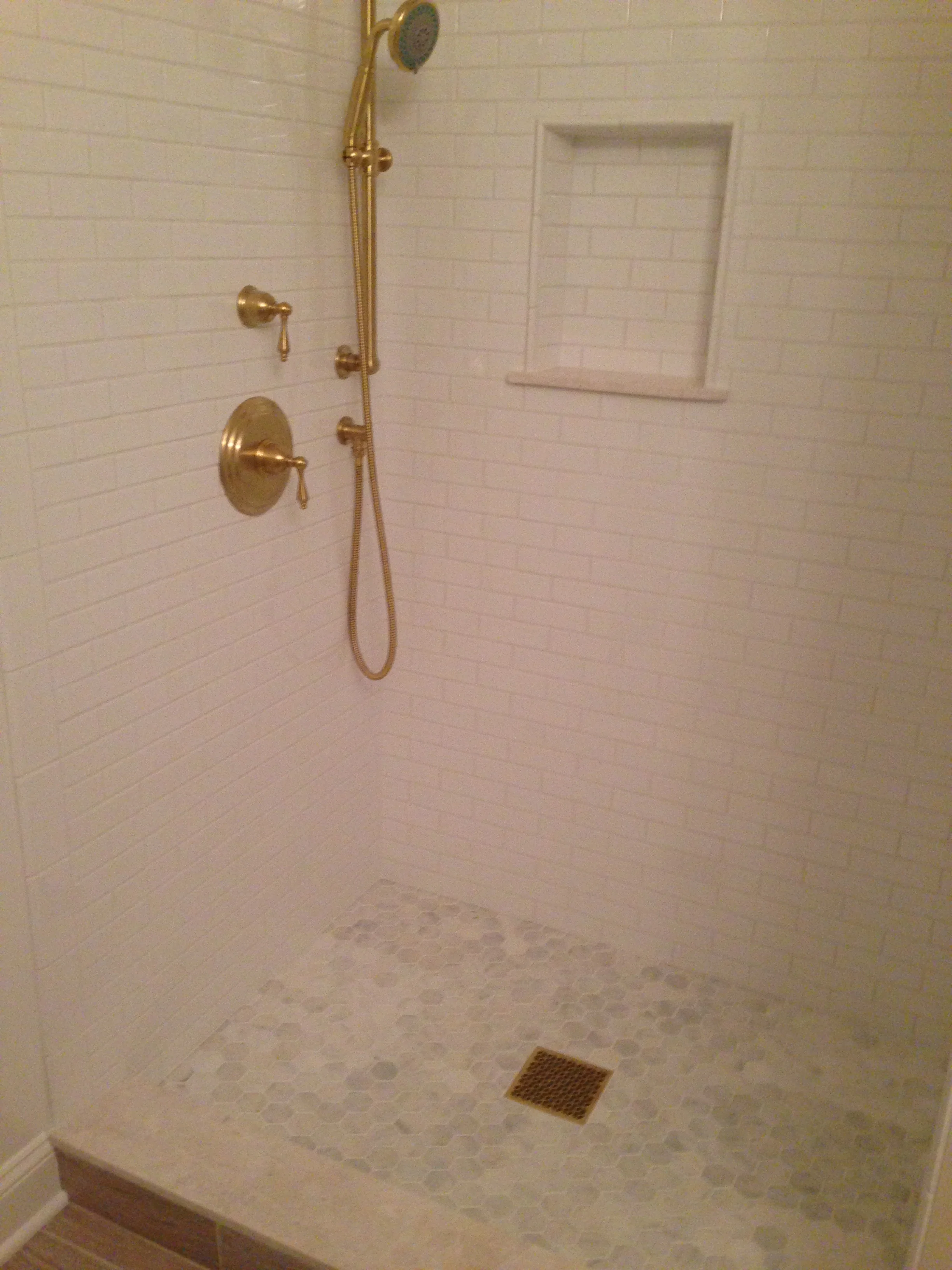 2x6 white gloss with marble hex on the floor; satin brass fittings.