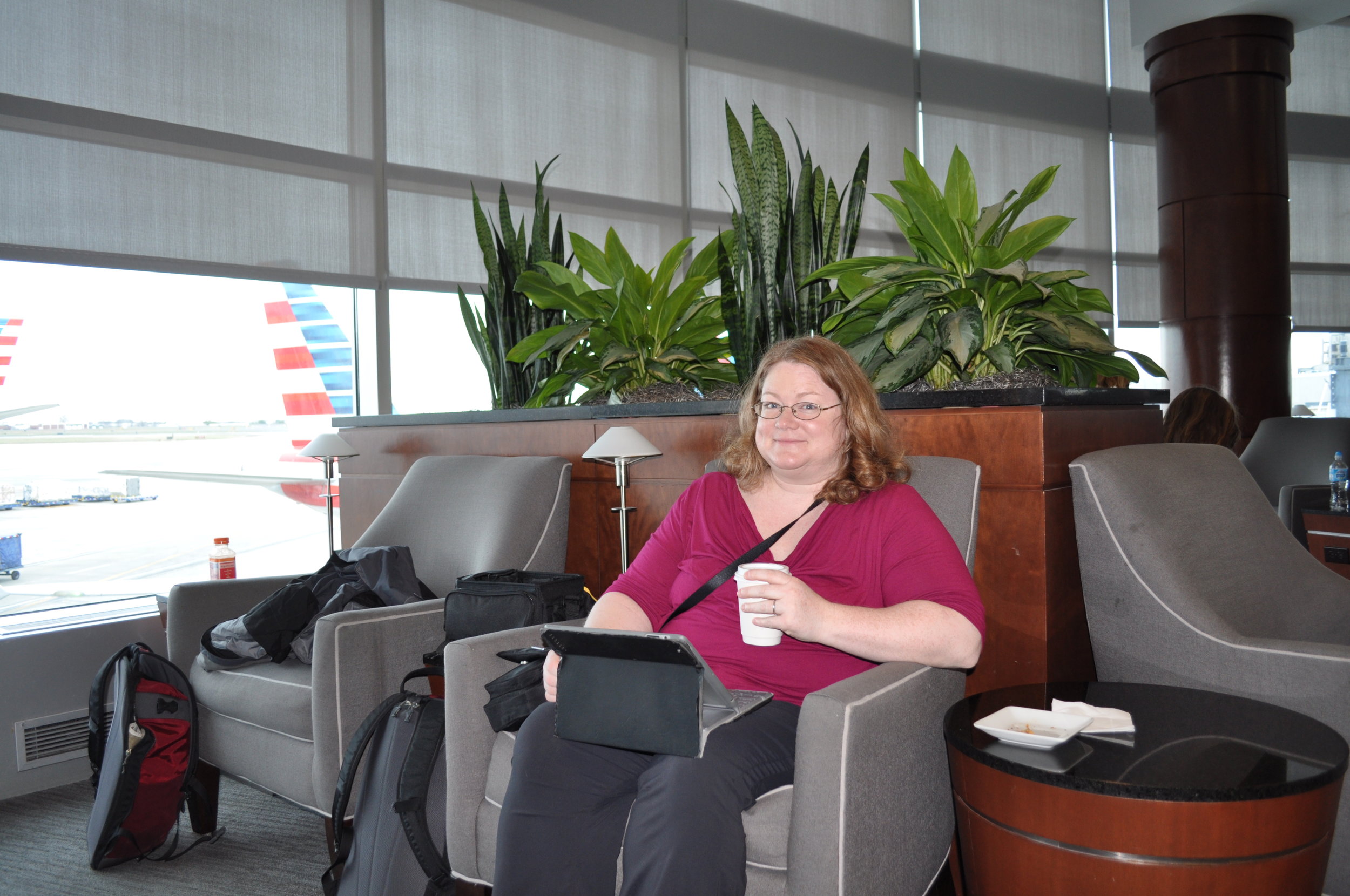 Dianne with a cup of coffee and Facebook in the American lounge at CLT