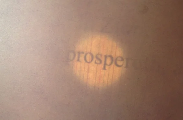 Shining a flashlight from behind the paper illuminates the words.