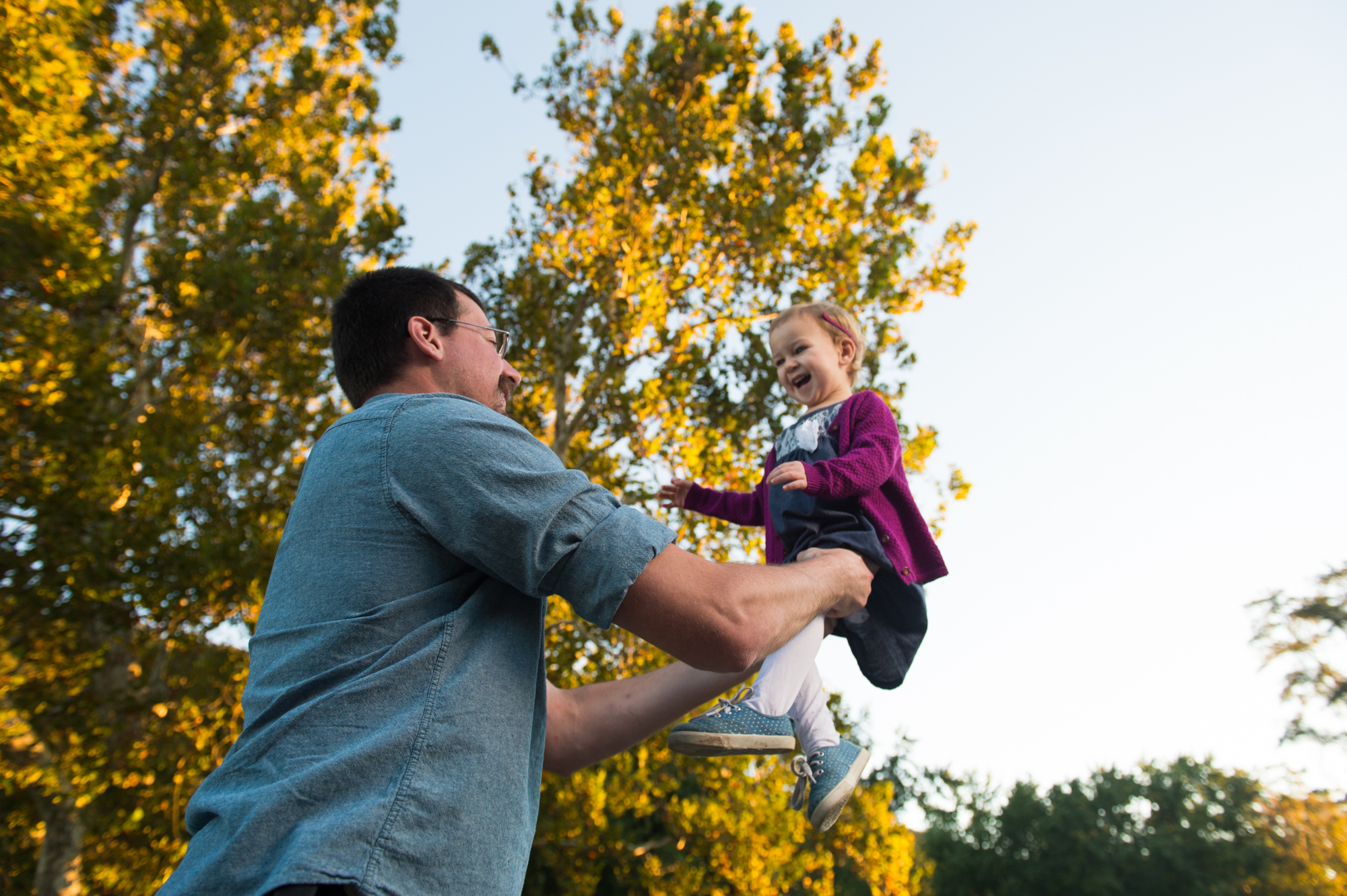 A father tossing his young daughter into the air during a family photo shoot