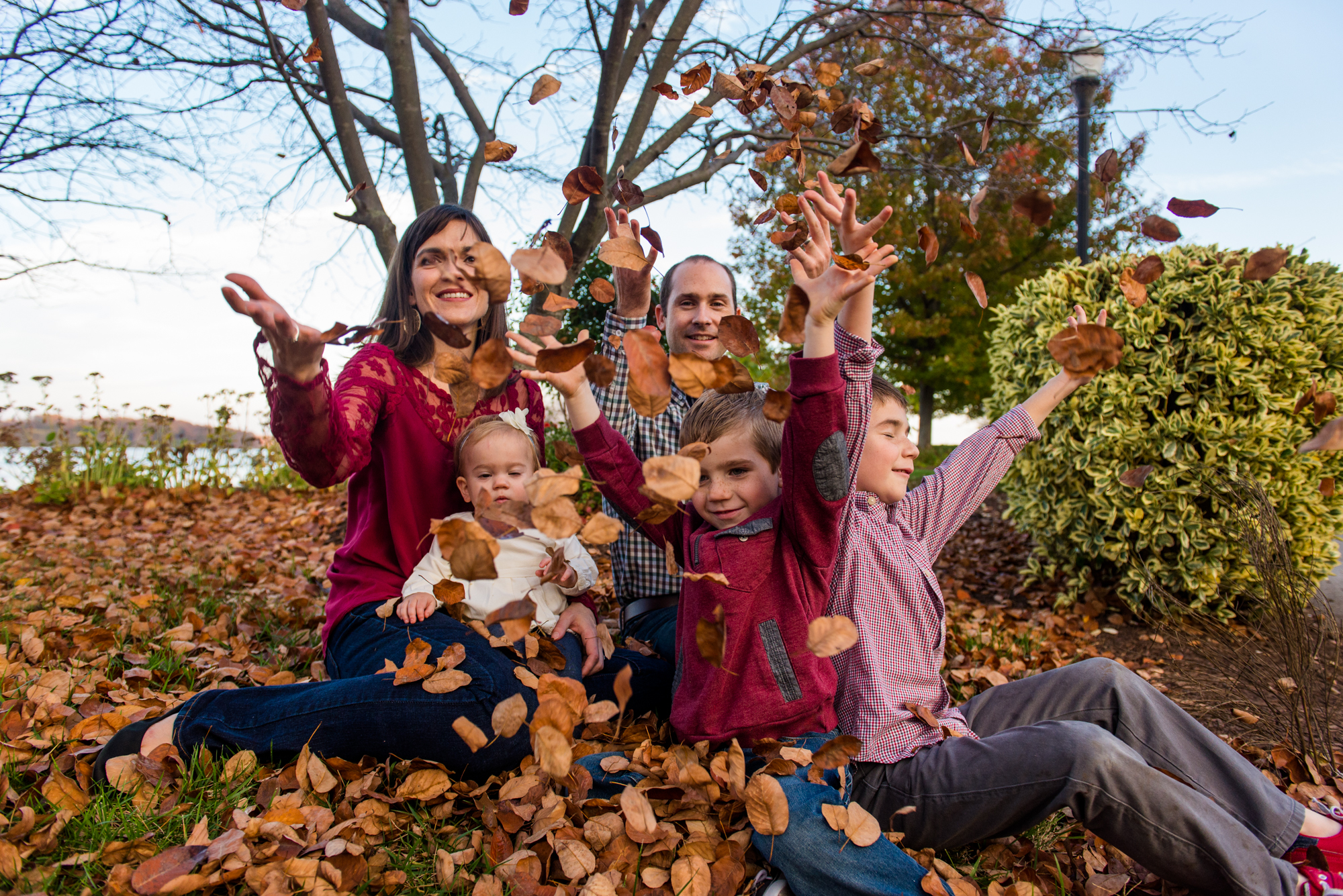 A family of 5 playing in the fall leaves