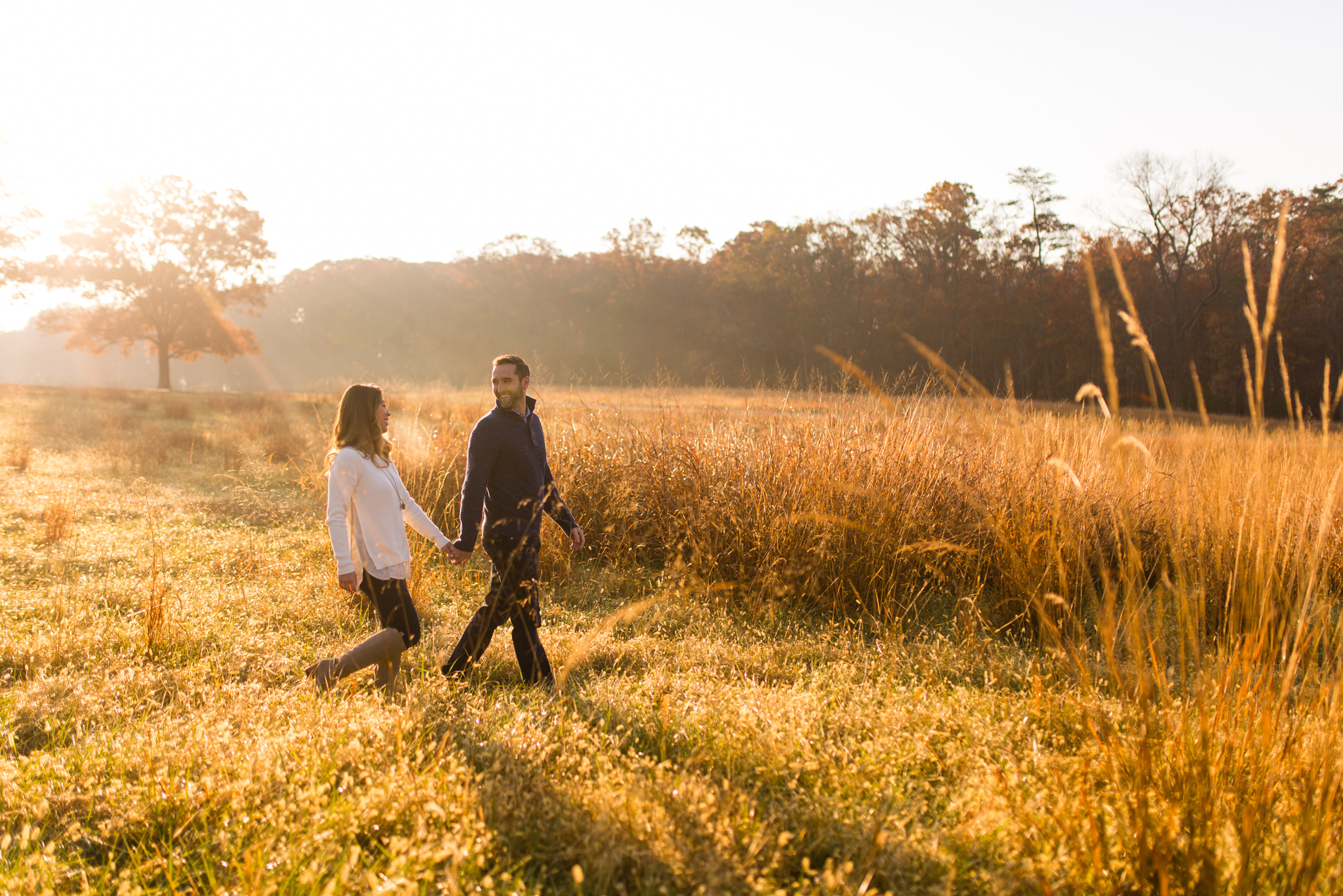 A couple walking hand in hand through a field