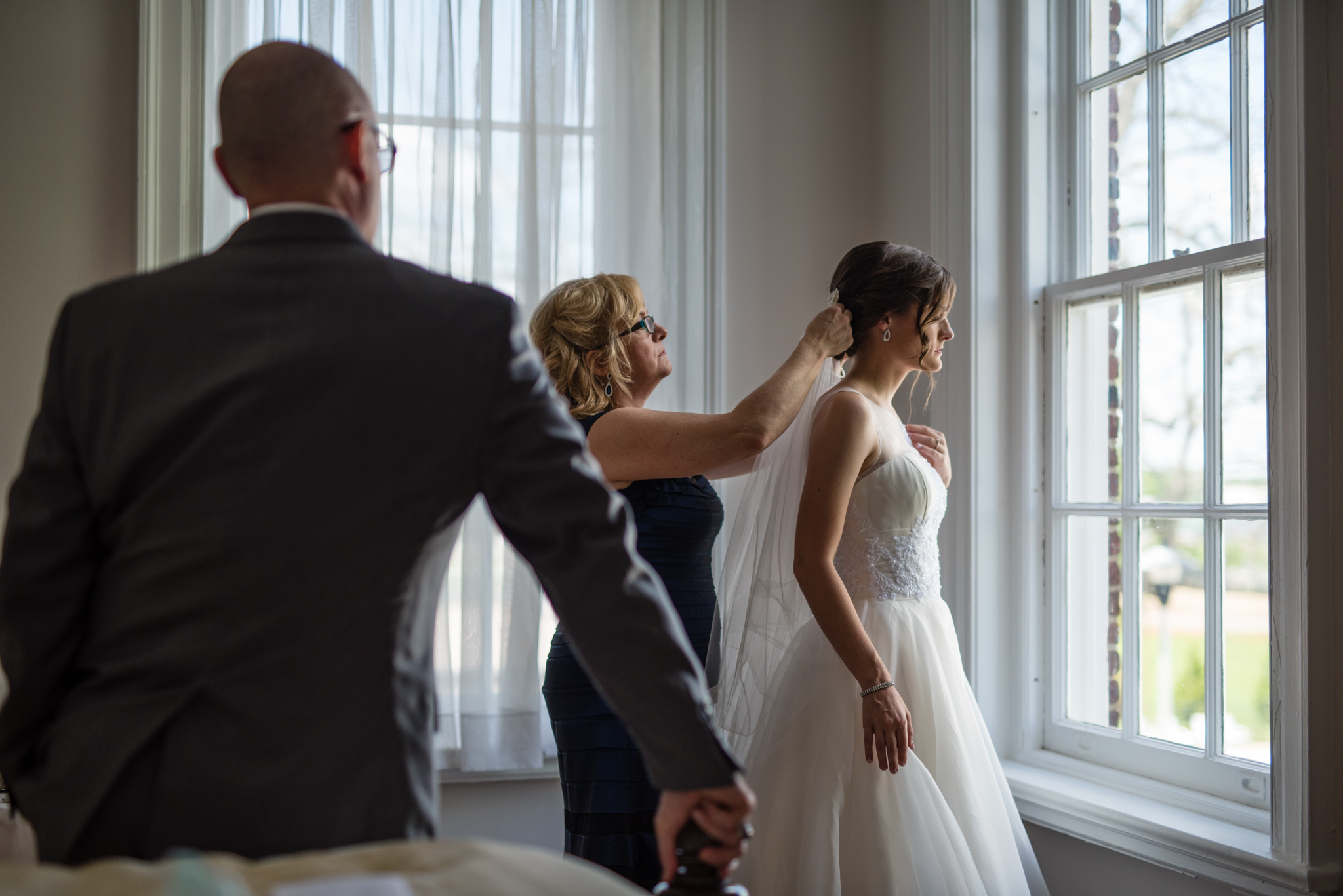 Bride putting on veil before wedding