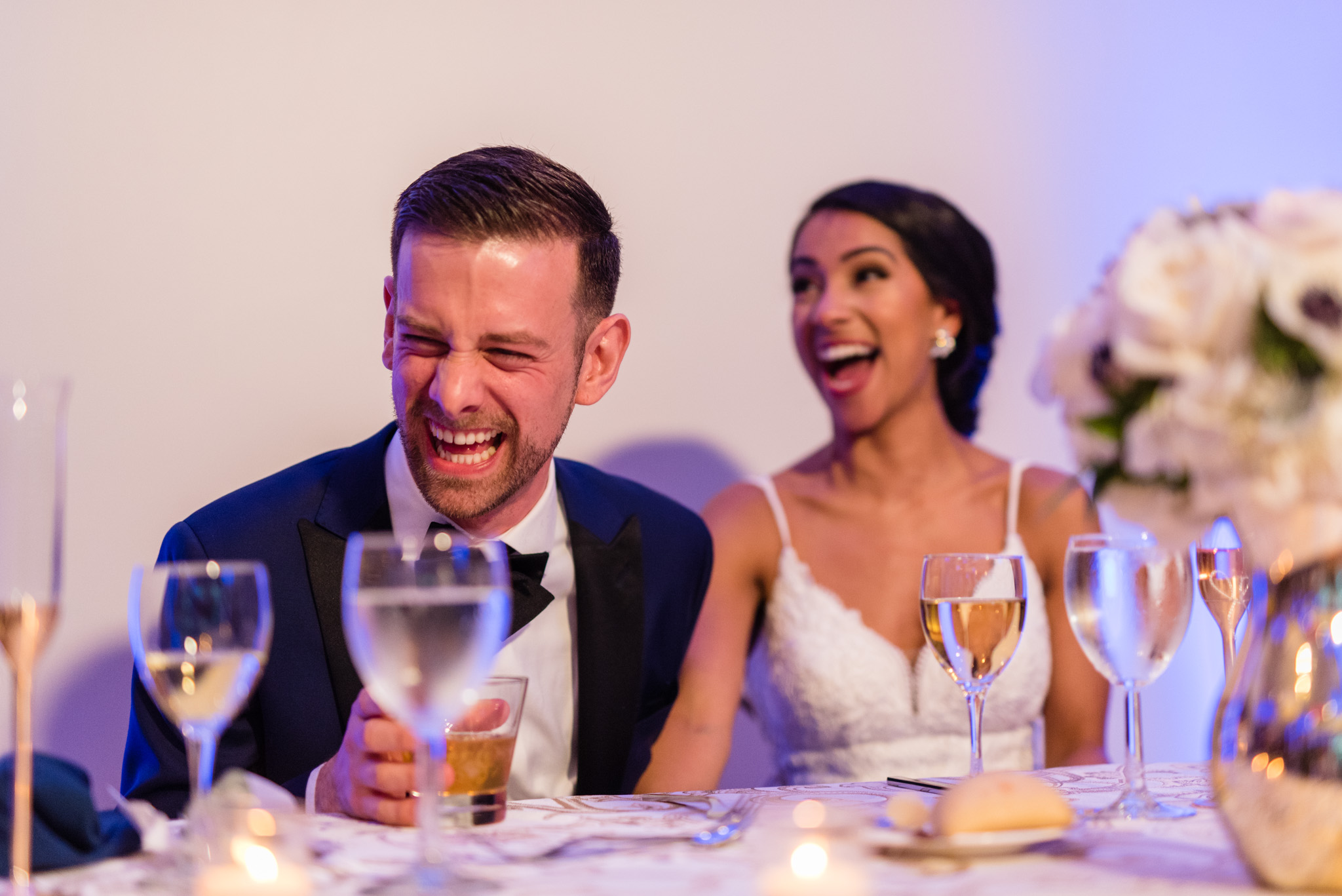 The bride and groom react with laughter to the wedding speeches