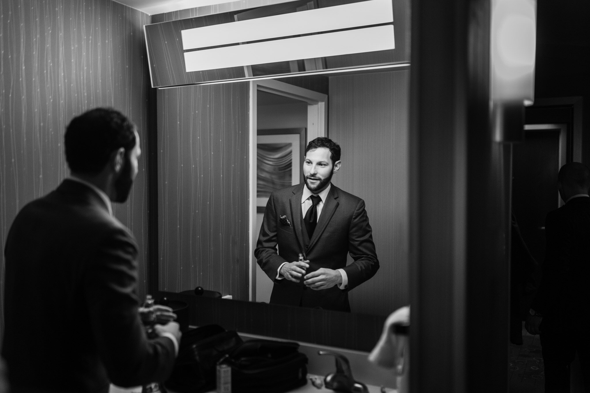 black and white photo of the groom getting ready in a mirror