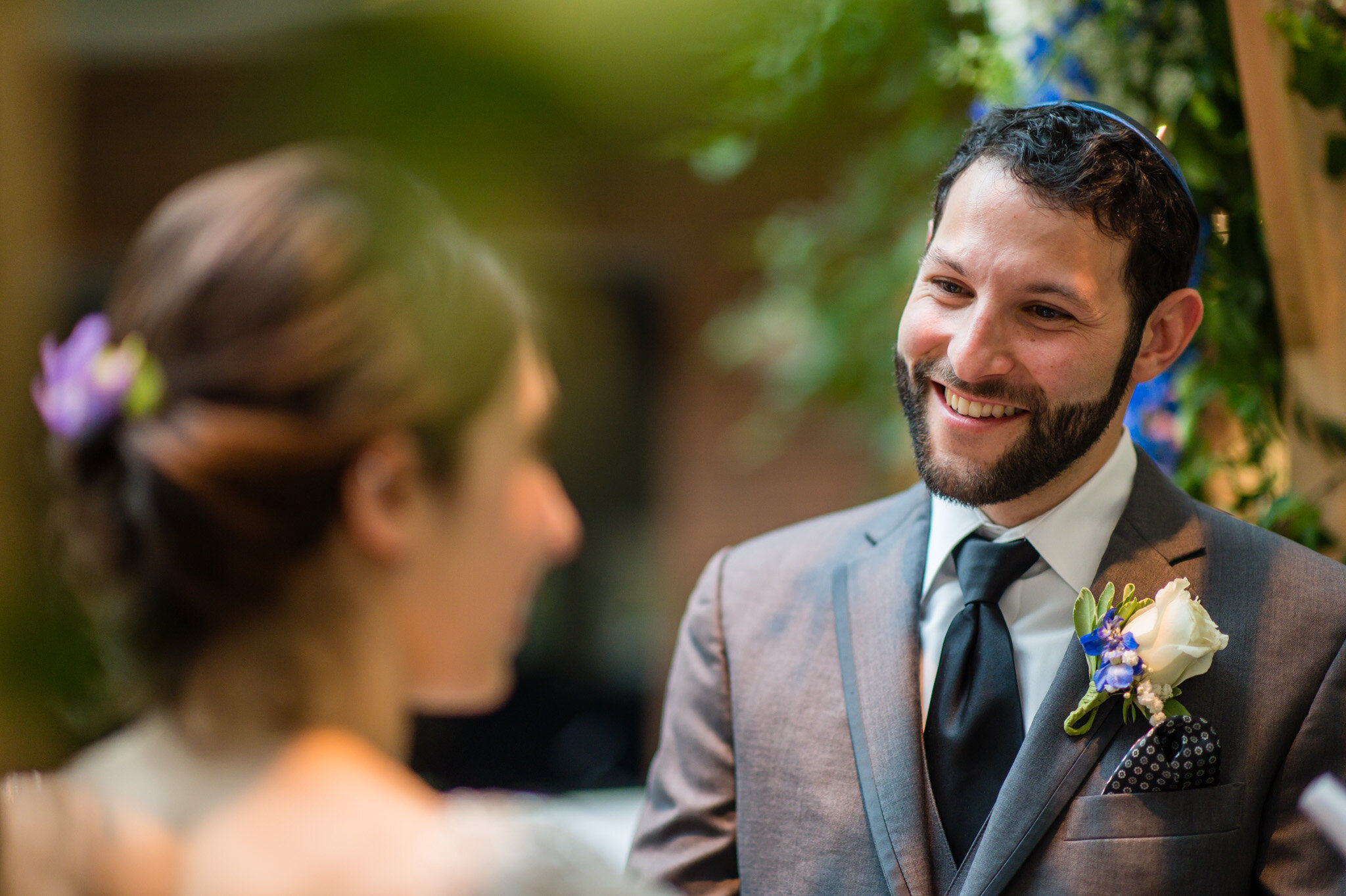 The groom smiles as his bride at their Jewish wedding ceremony
