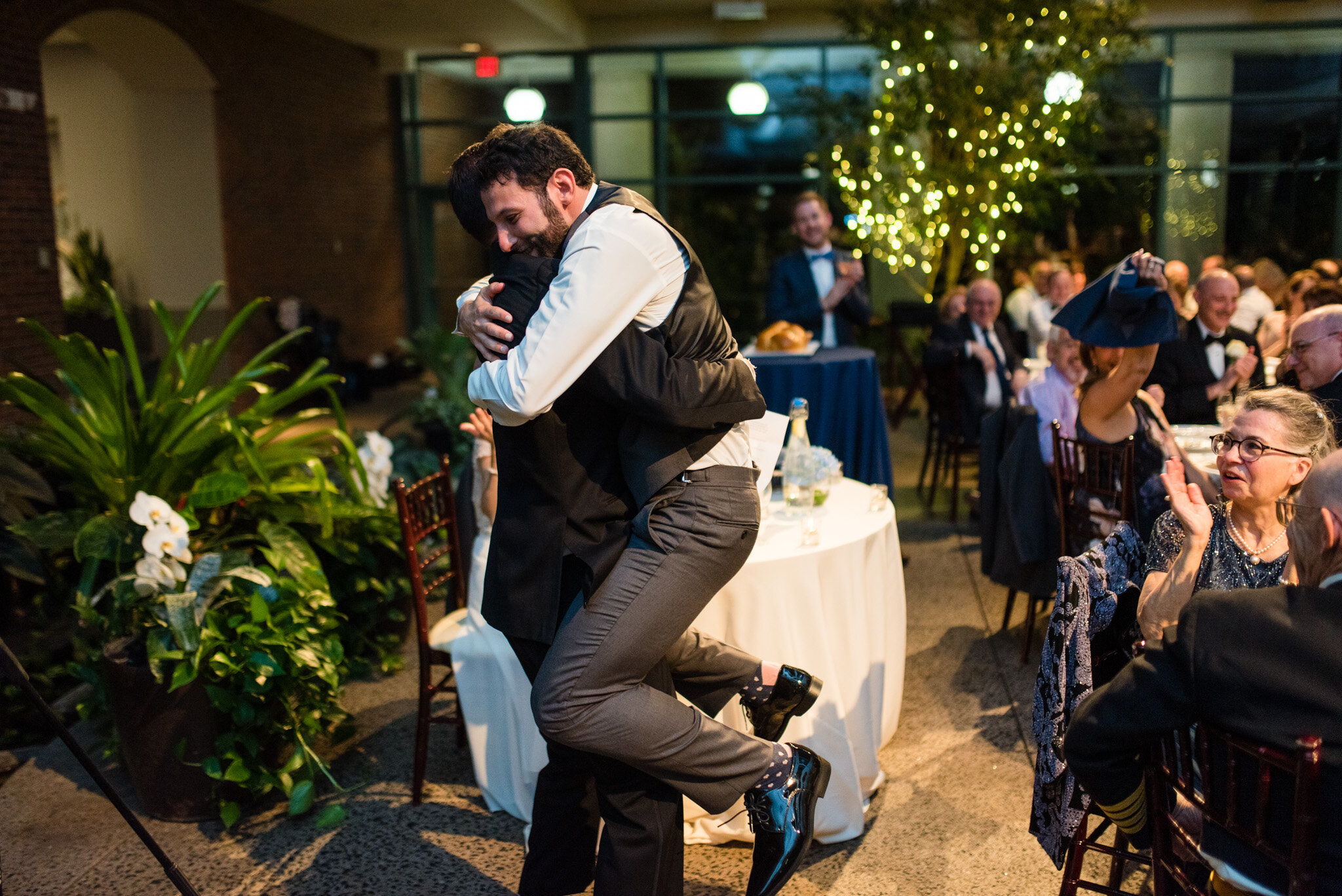 The groom hugs his best man at his wedding reception