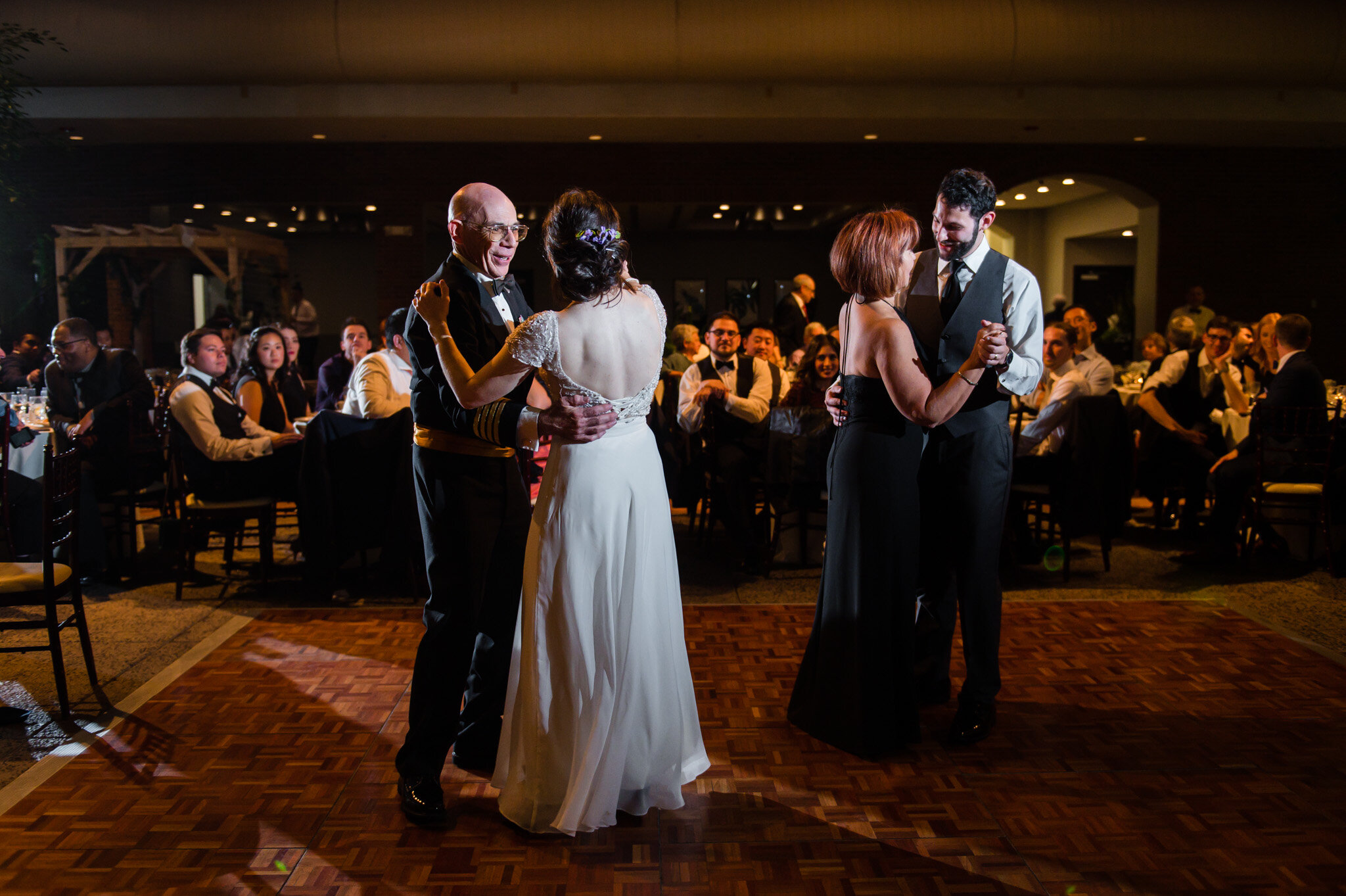 The bride and groom share a dance with their parents 