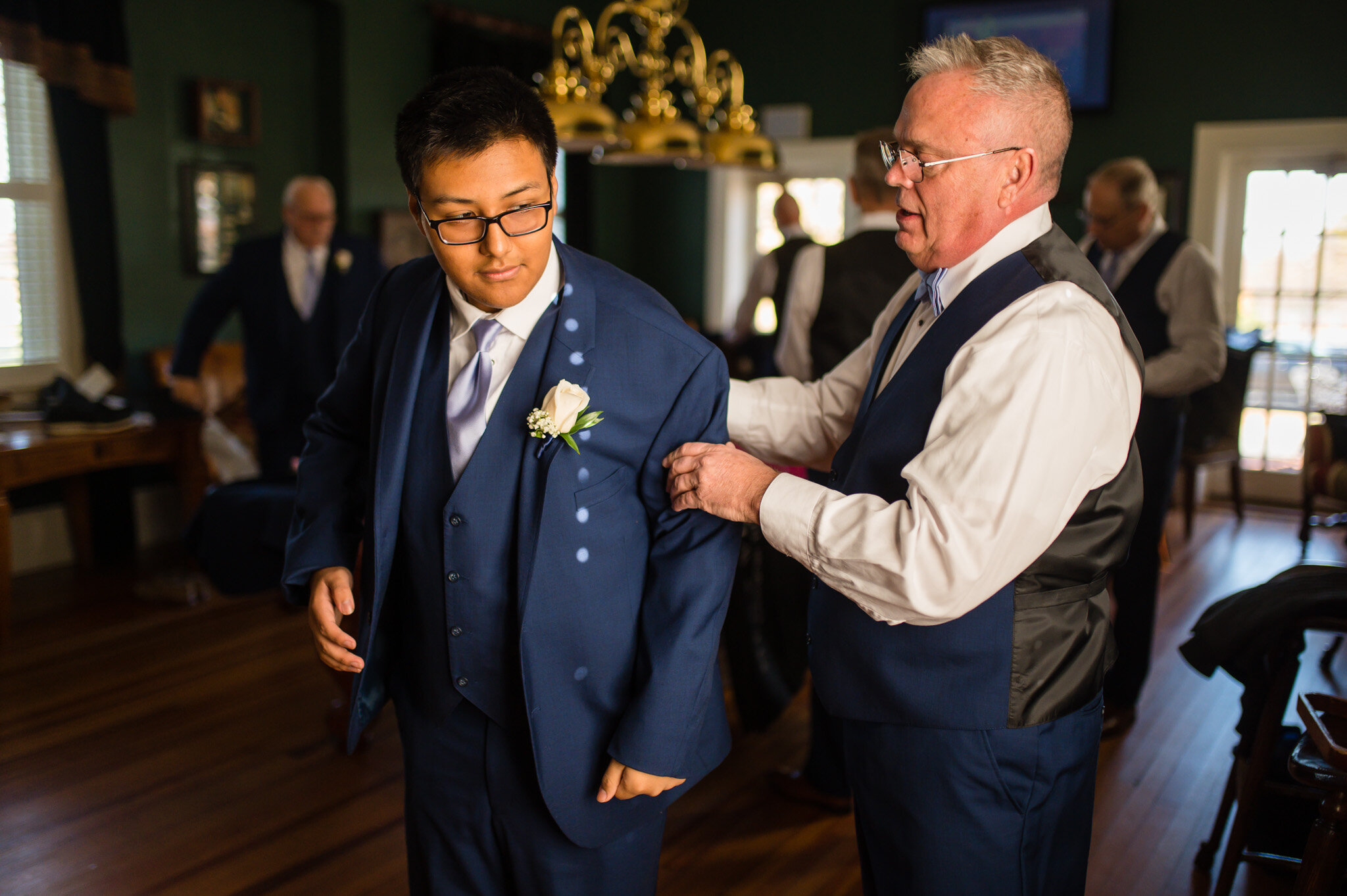 Groom and son helping to put on their suit coats on their wedding day.