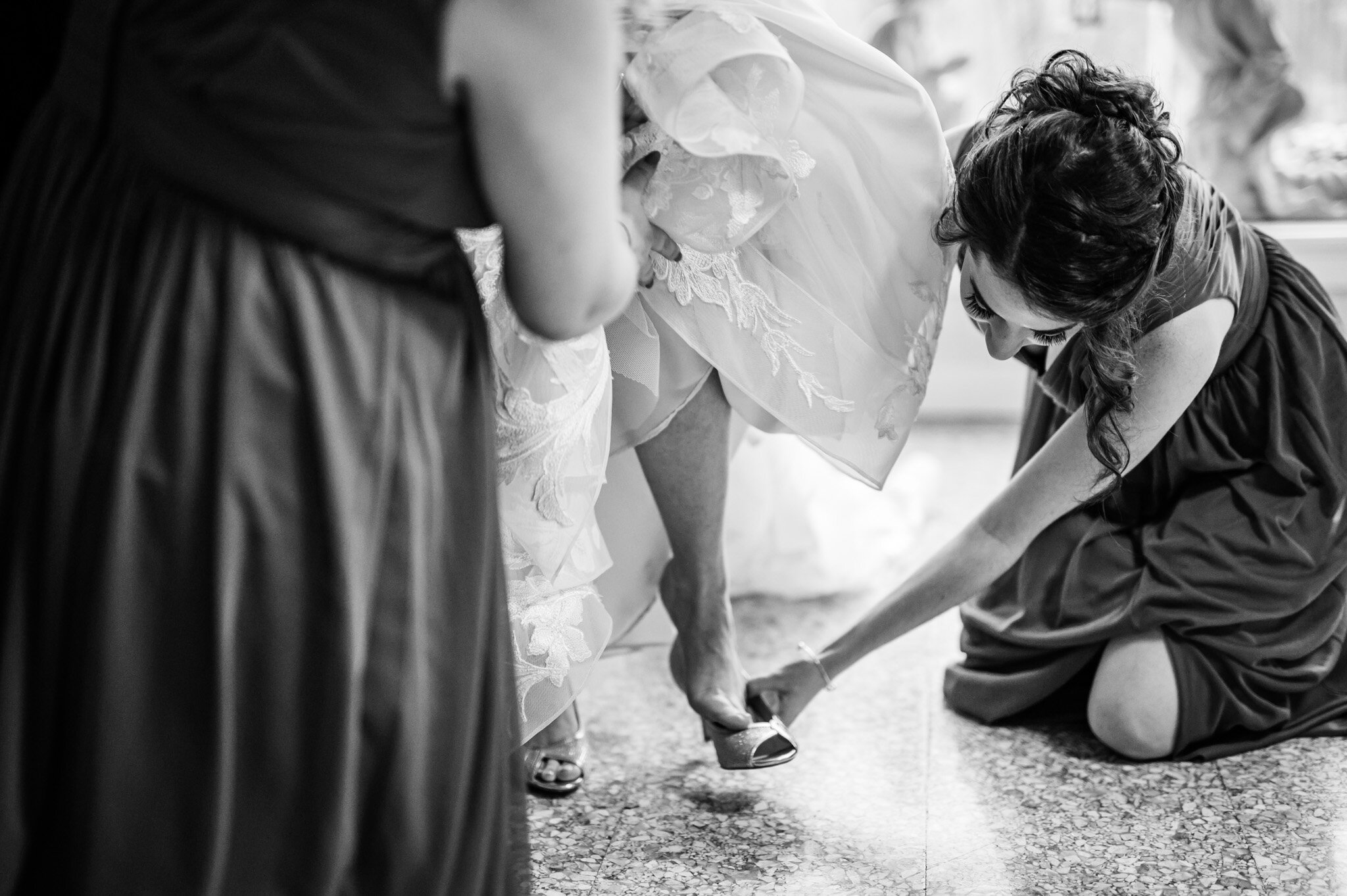 Bridesmaid helping the bride to put on her wedding shoes