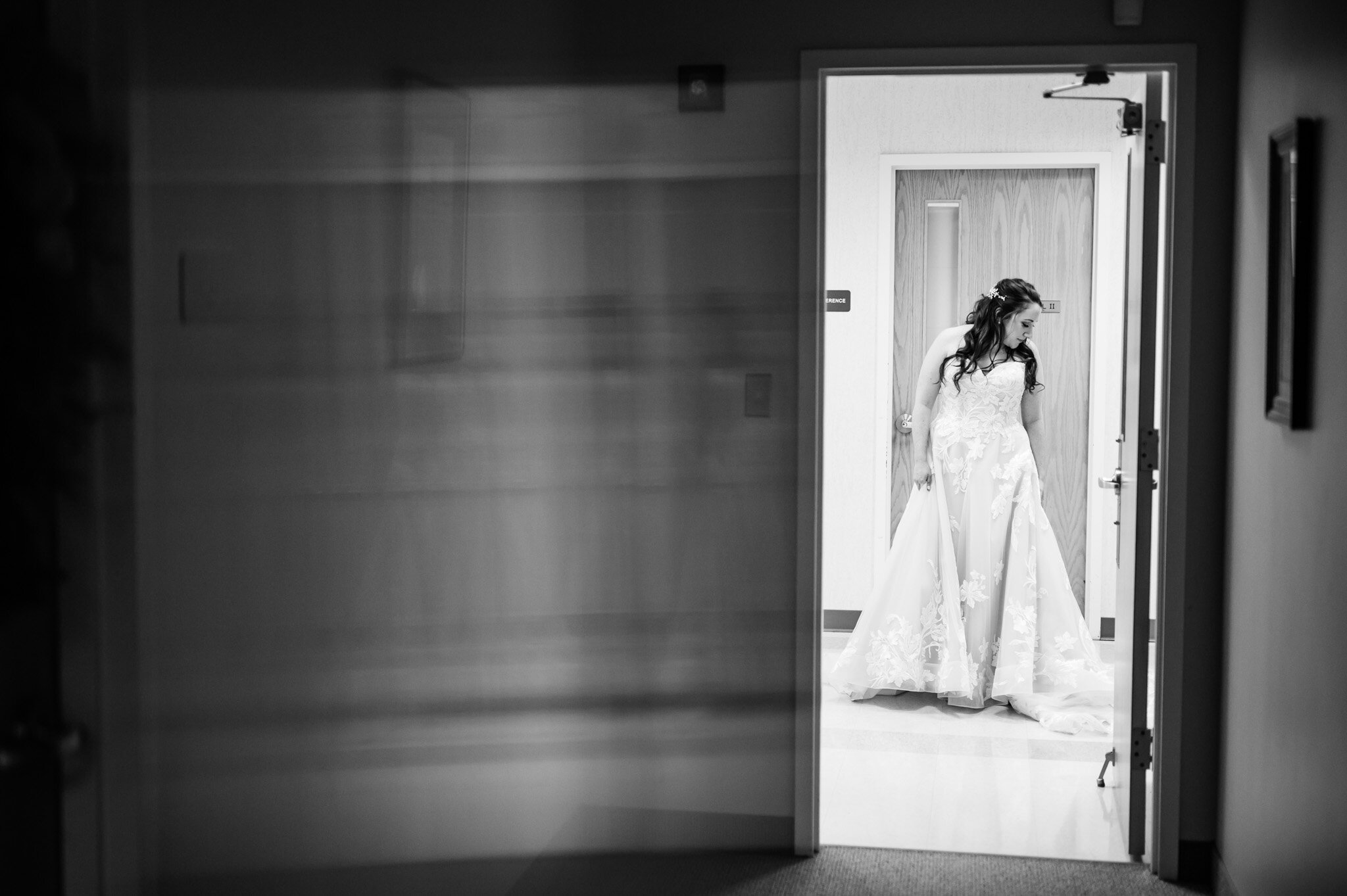Black and white of bride admiring her dress