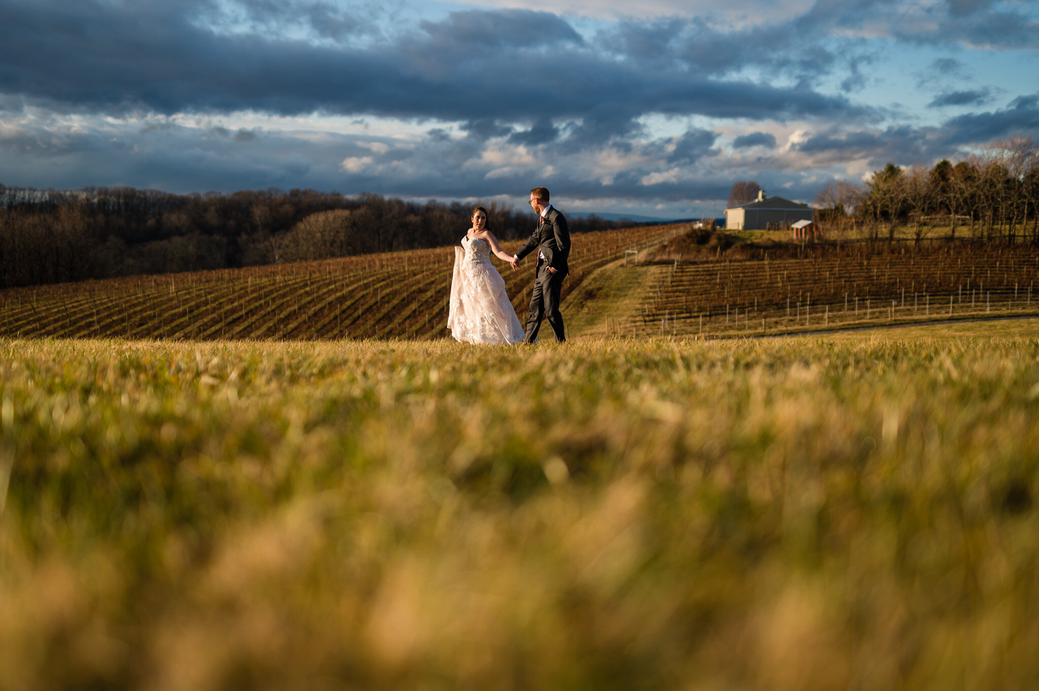 The bride and groom walking together through a field.