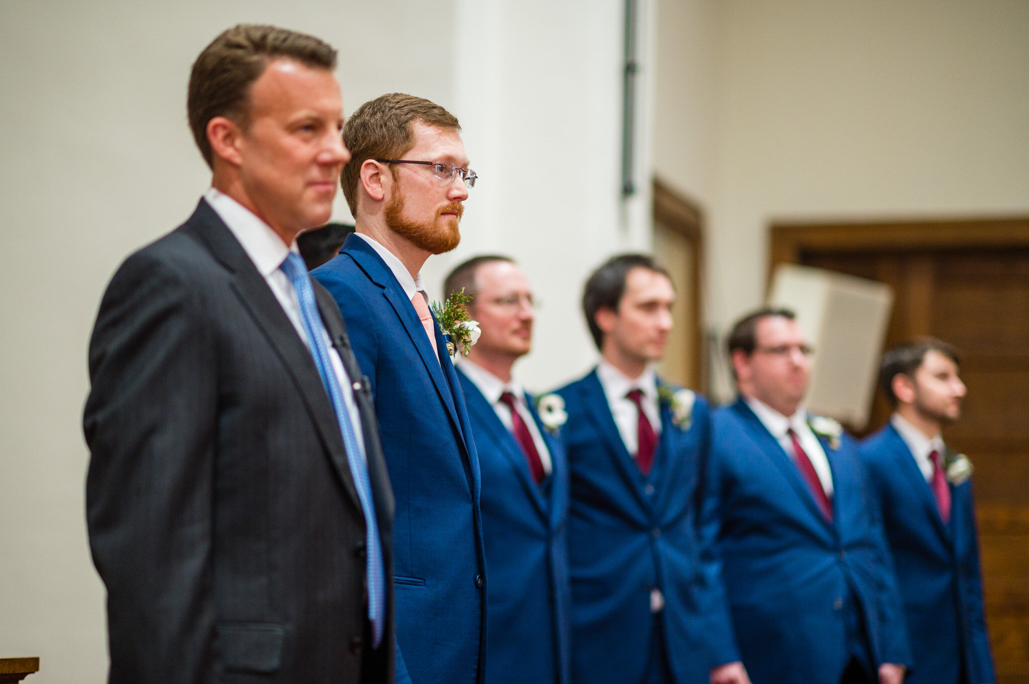 The groom and groomsmen watch the bride walking down the aisle.