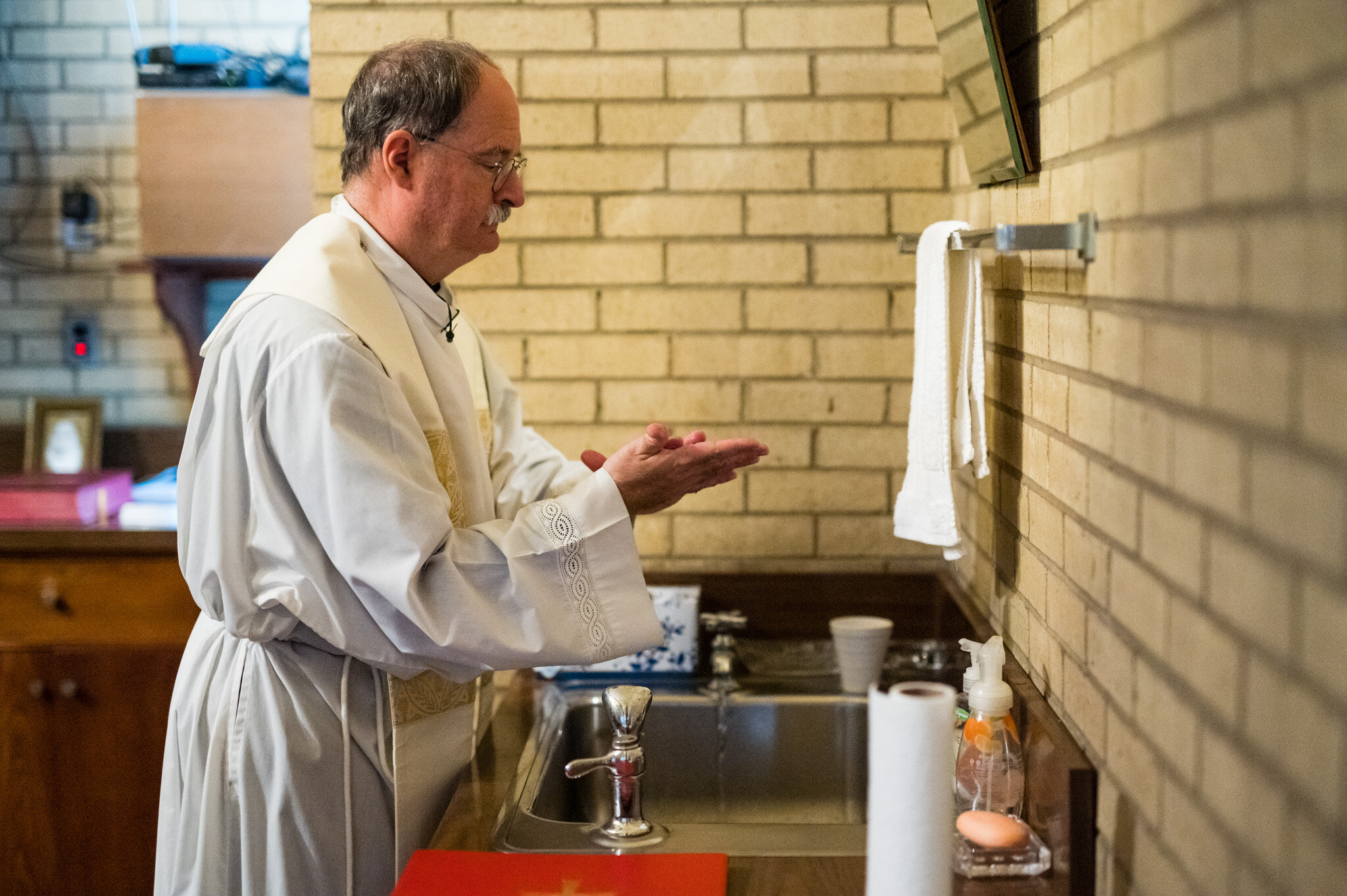 A priest washes his hands before an elopement ceremony during COVID-19