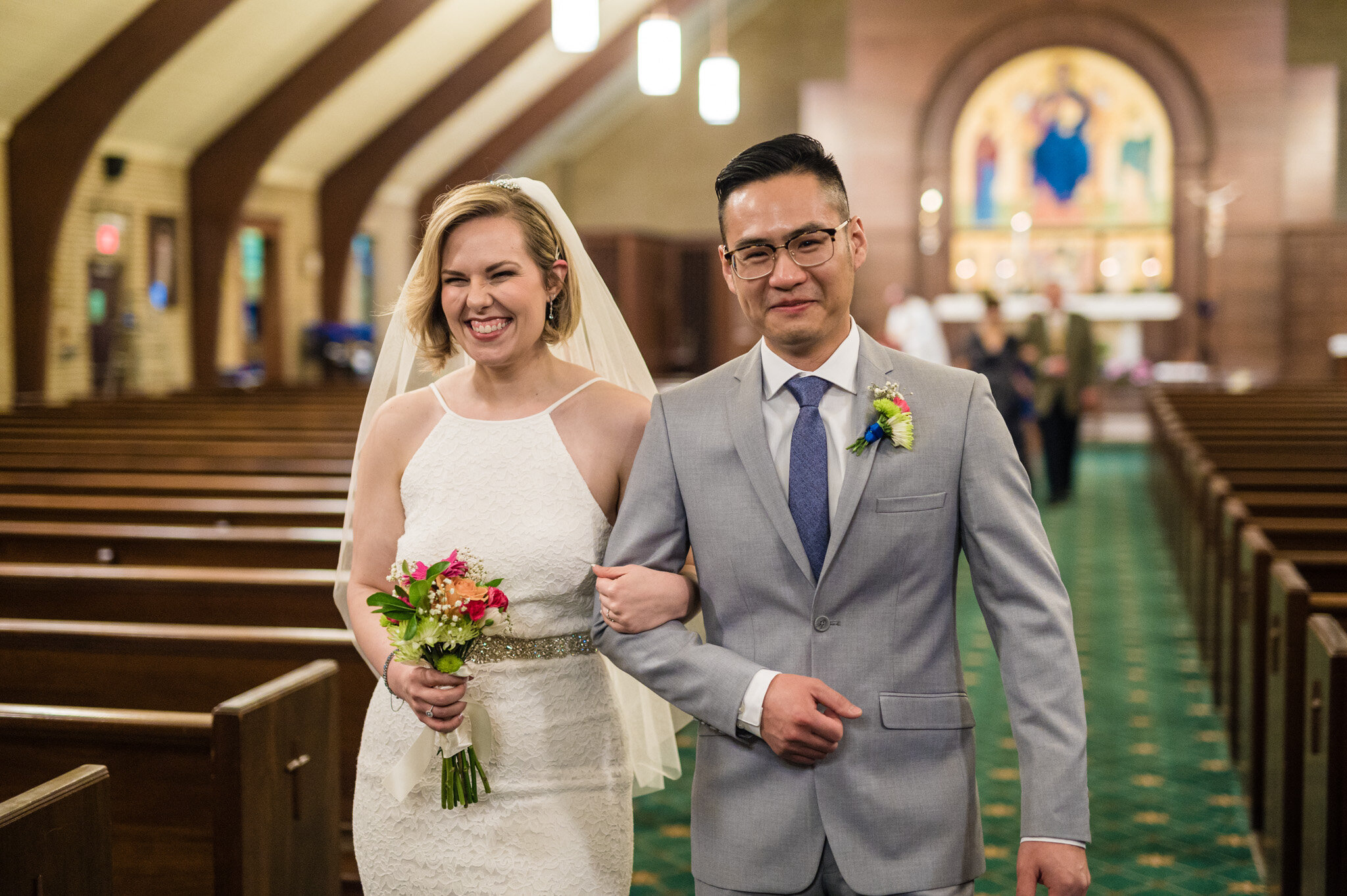 A bride and groom excitedly walk out of the ceremony