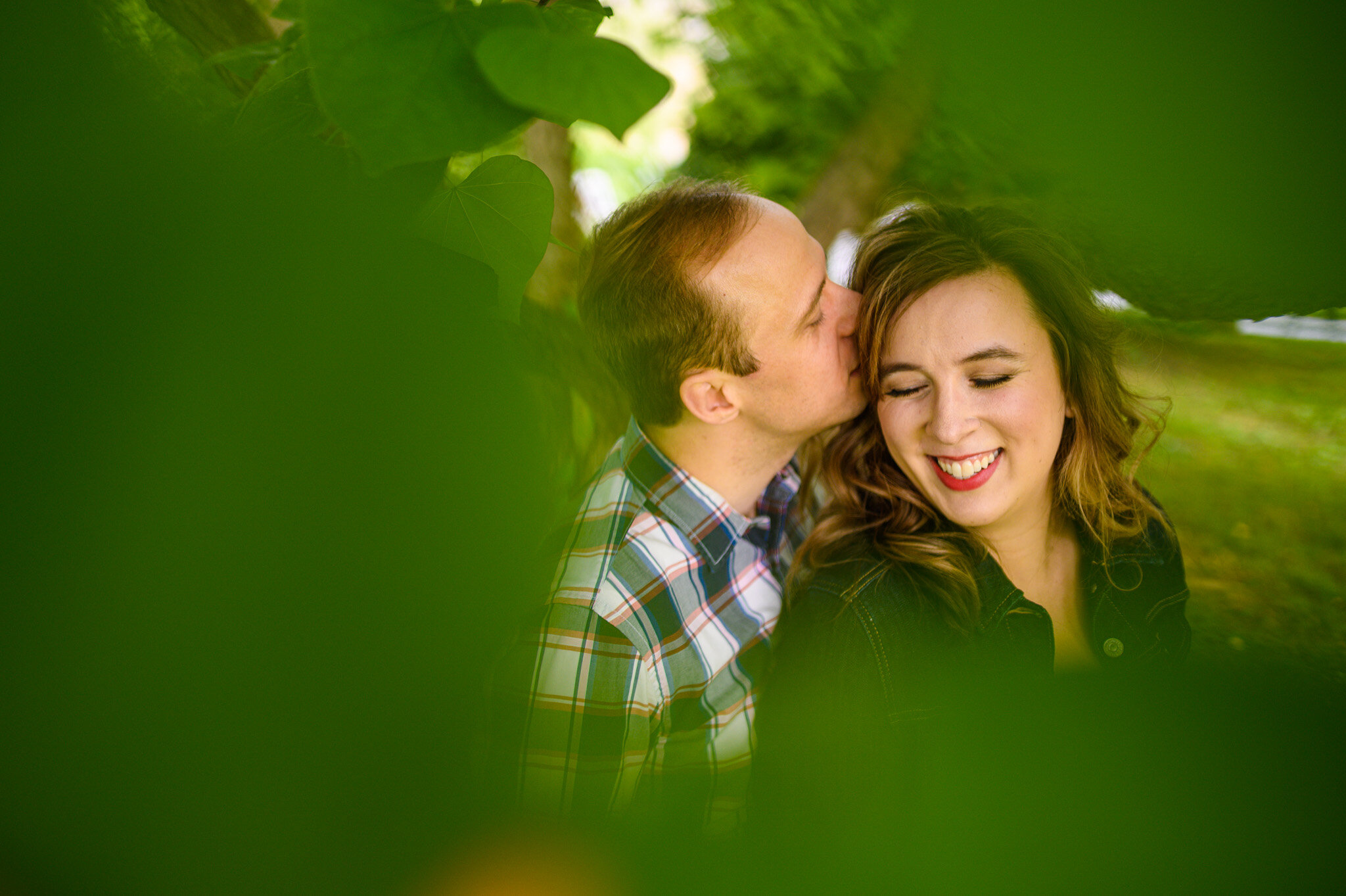 Outdoor engagement session looking through the leaves of a tree.