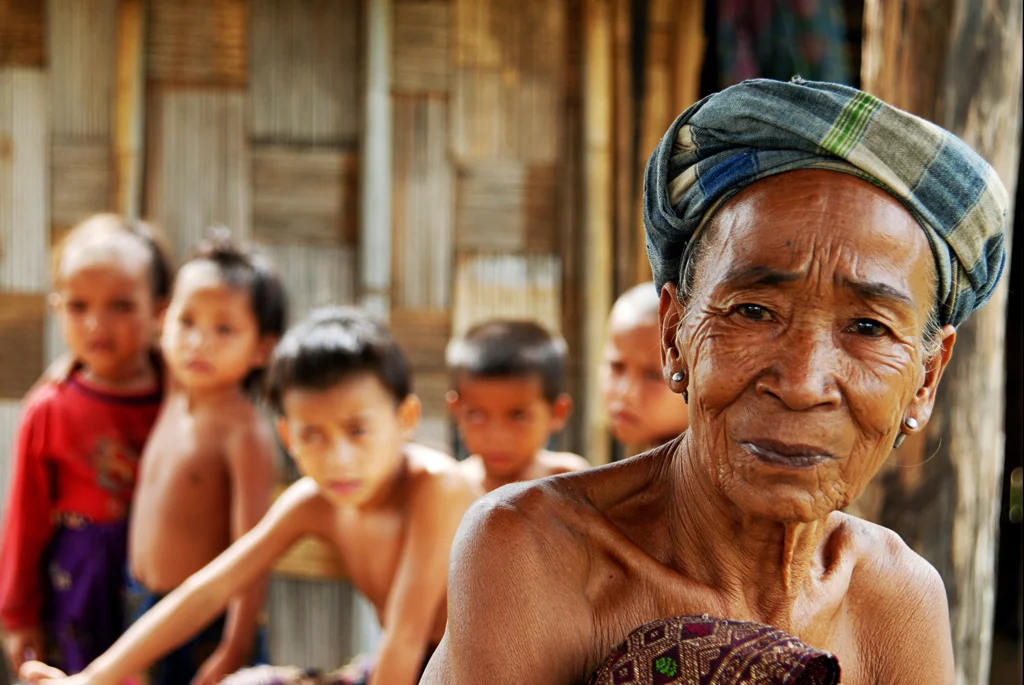 A grandmother sits with her grandchildren as their land is cleared of UXO which will enable to
them to farm safely. Savannakhet Province, Laos.