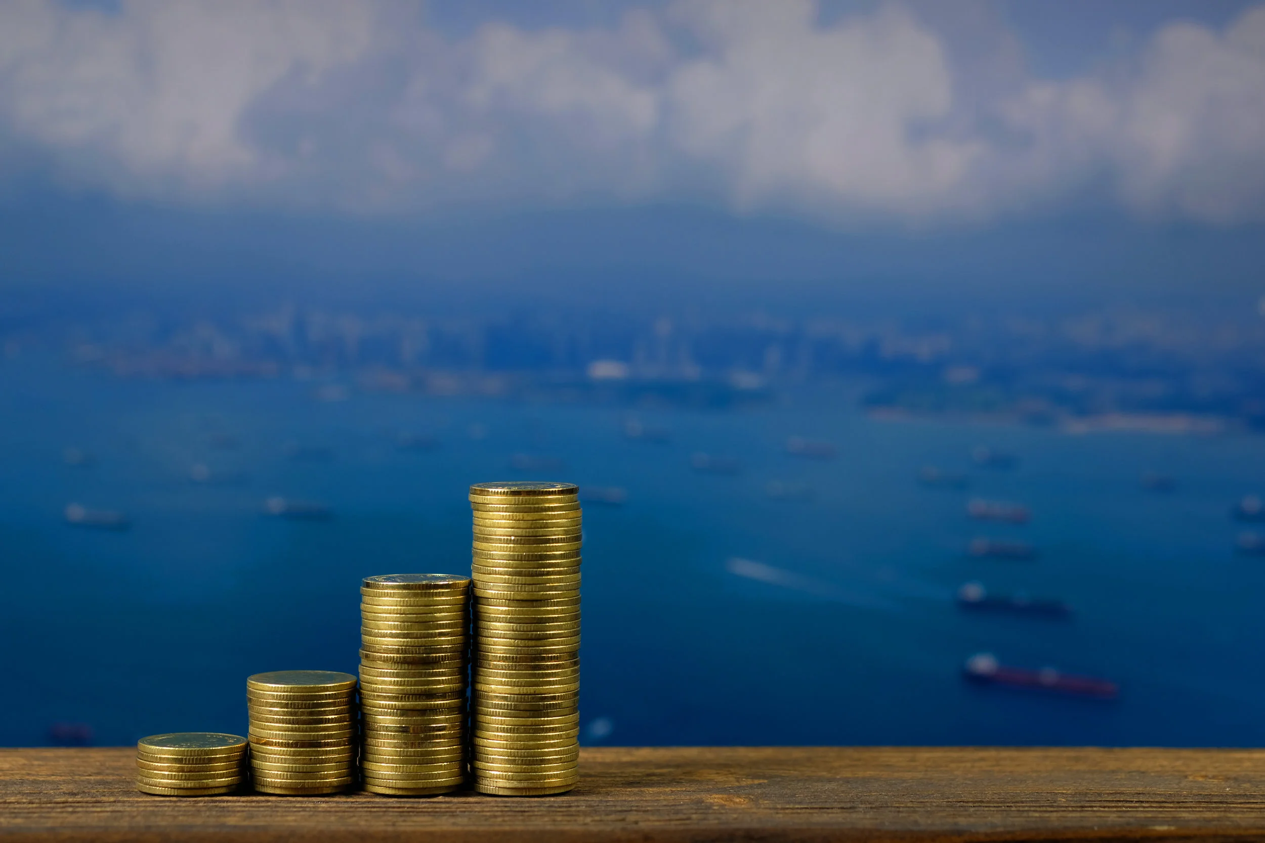 Step of coin stack on top wooden working table over seascape and