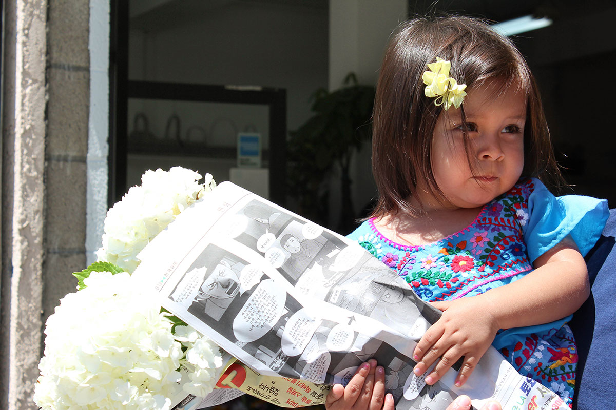 My daughter dressed like a Mexican while holding fresh flowers wrapped in a Japanese newspaper circa 2011.