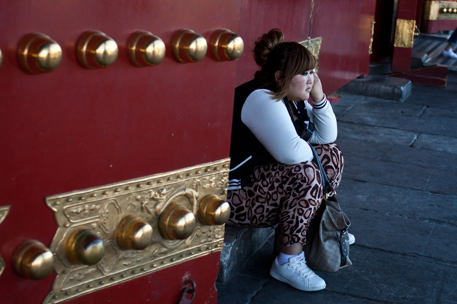 bored looking teenager at the gates of the forbidden city. probably being dragged round on one of the popular Chinese cultural tours of the city.