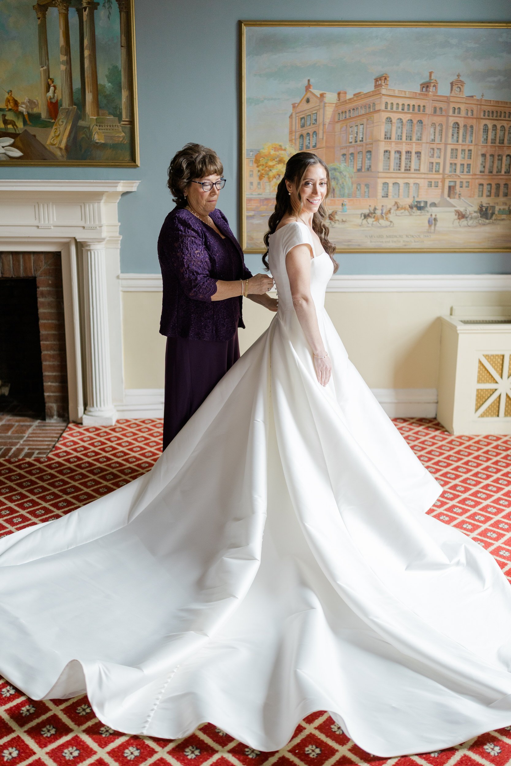 Bride's mom helps her put on her wedding dress at the Harvard Club of Boston Wedding