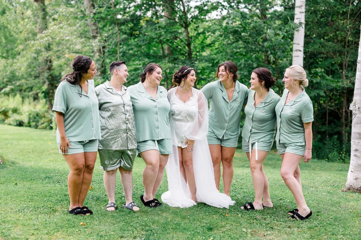 Bride and bridesmaids smile in matching green pajamas at Mountain Top Inn Vermont Wedding