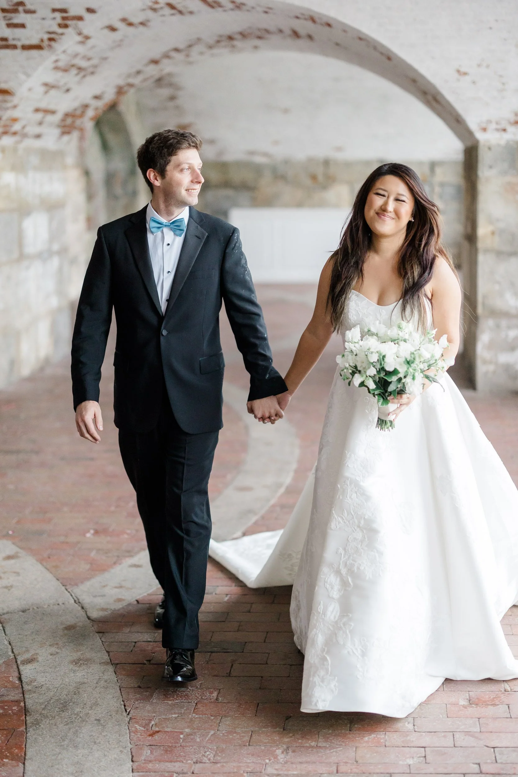 Bride and groom smile together before their wedding ceremony at Fort Adams