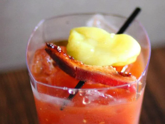 Backyard Mary by Mia Sarazen, a Bloody Mary variation with Sailor Jerry, heirloom tomato, Tabasco, black pepper, honey, beer, BBQ sauce, bacon garnish.