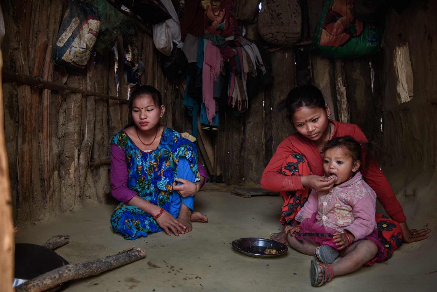  Ganga Maskimagar (17) helps her sister Kalpana Paharaimagar (19) at her home in Majhi Shivir, Chaumala, Kailali, Nepal. Both Ganga and Kalpana's husbands work in India to support their families. 
