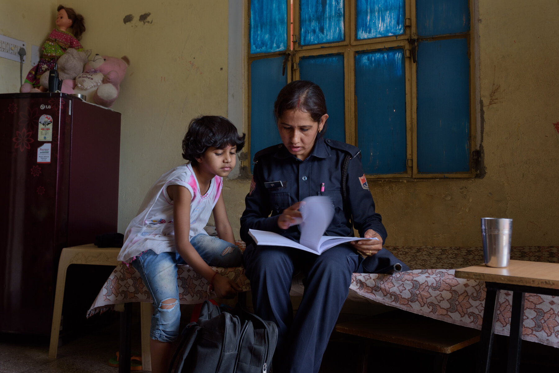  Jhooma Mena, 29, checks her seven year old daughter Devanshi's homework before leaving for patrolling duty. 