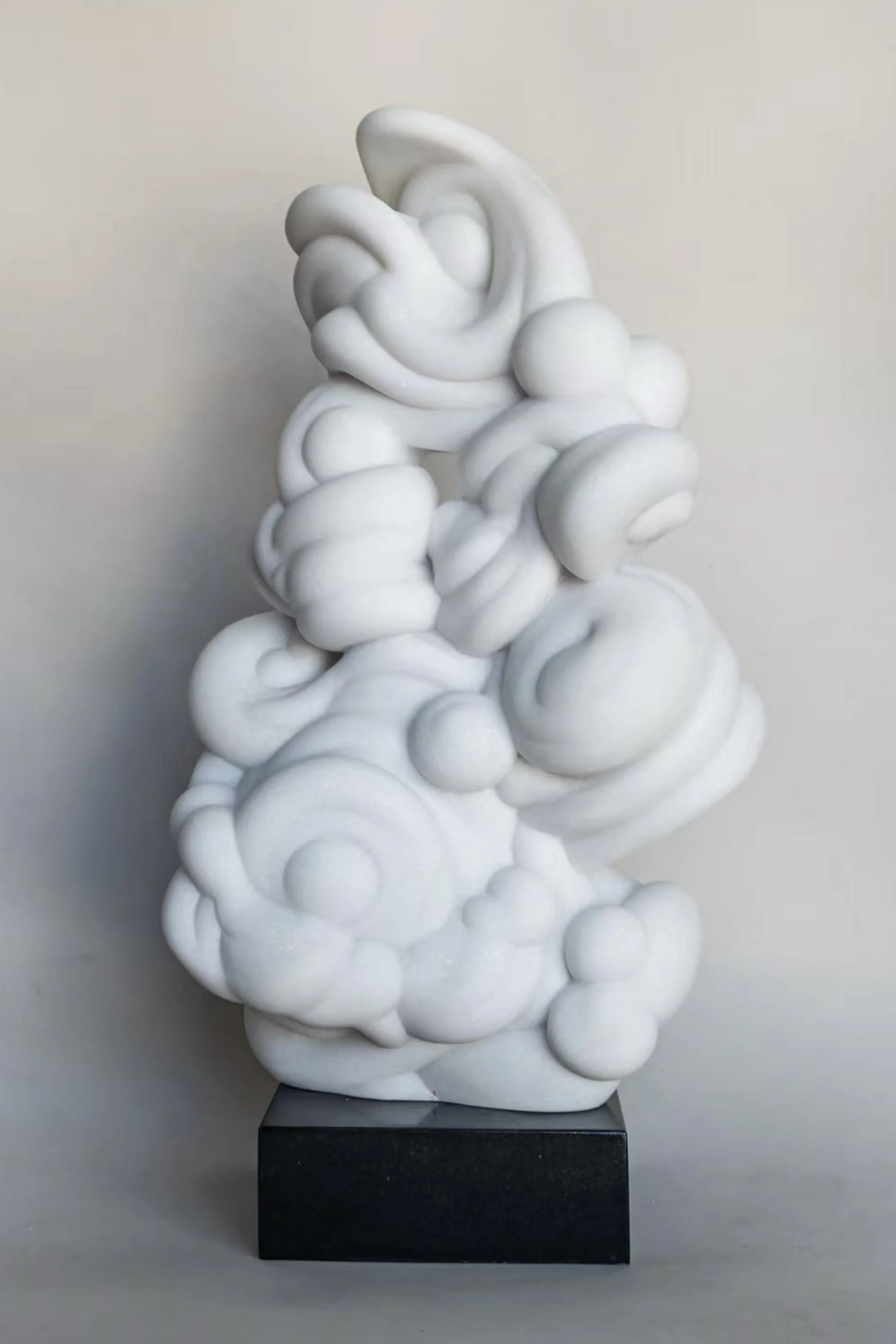 White abstract sculpture with rounded, cloud-like forms on a black rectangular base.