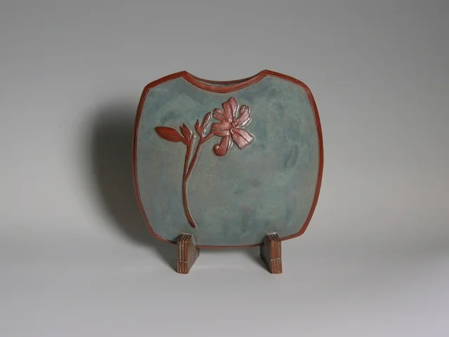 Normal
0
0
1
25
150
UMD
4
1
177
10.1316
 
 
0
0
0
 
Lily Pillow Vase   Description:  Red Earthenware Clay, stretched slab construction. Surface treatment: raised image with terra sigillata. Glazed on interior and exterior   …