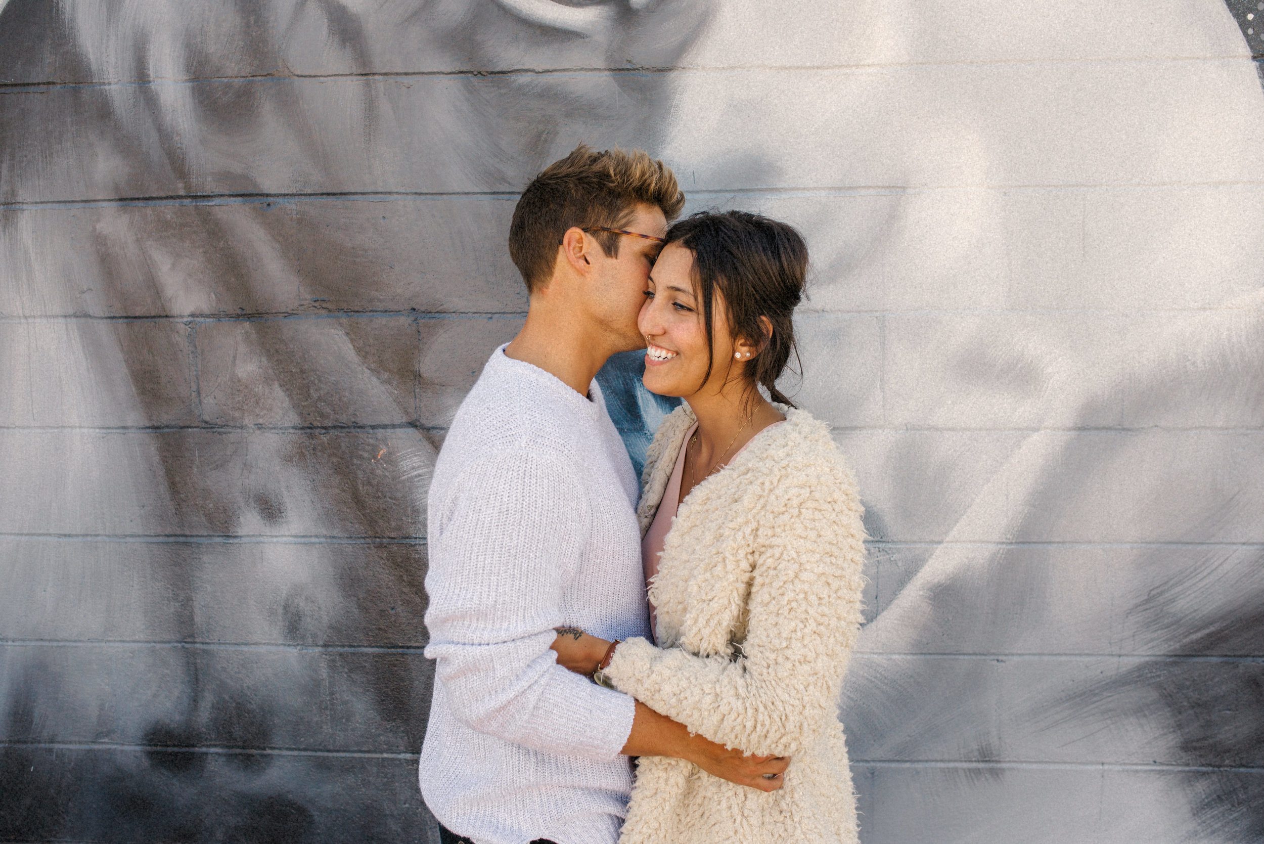  Bran + Hills embracing one another in front of graffiti wall in st pete florida - Naples Florida Wedding Photographer - Tampa Wedding Photographer - Stills by Hernan 