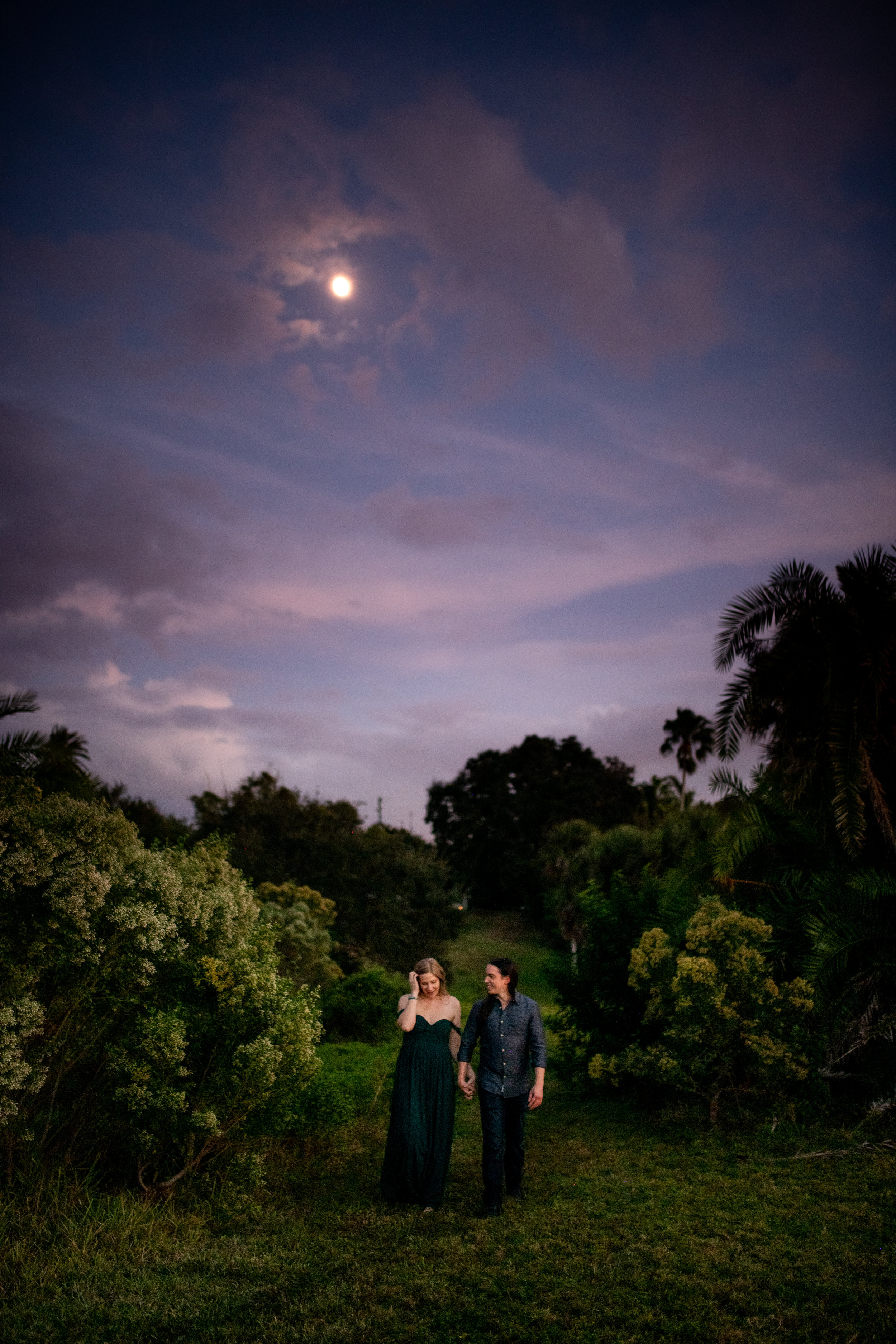  Couple walking down a grassy path under the moon 