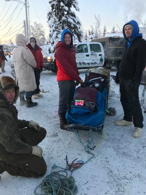 Liz talking to Ryne's Quest rider, Jim, while Derek, Ryne, and Tyler prepare the sled.