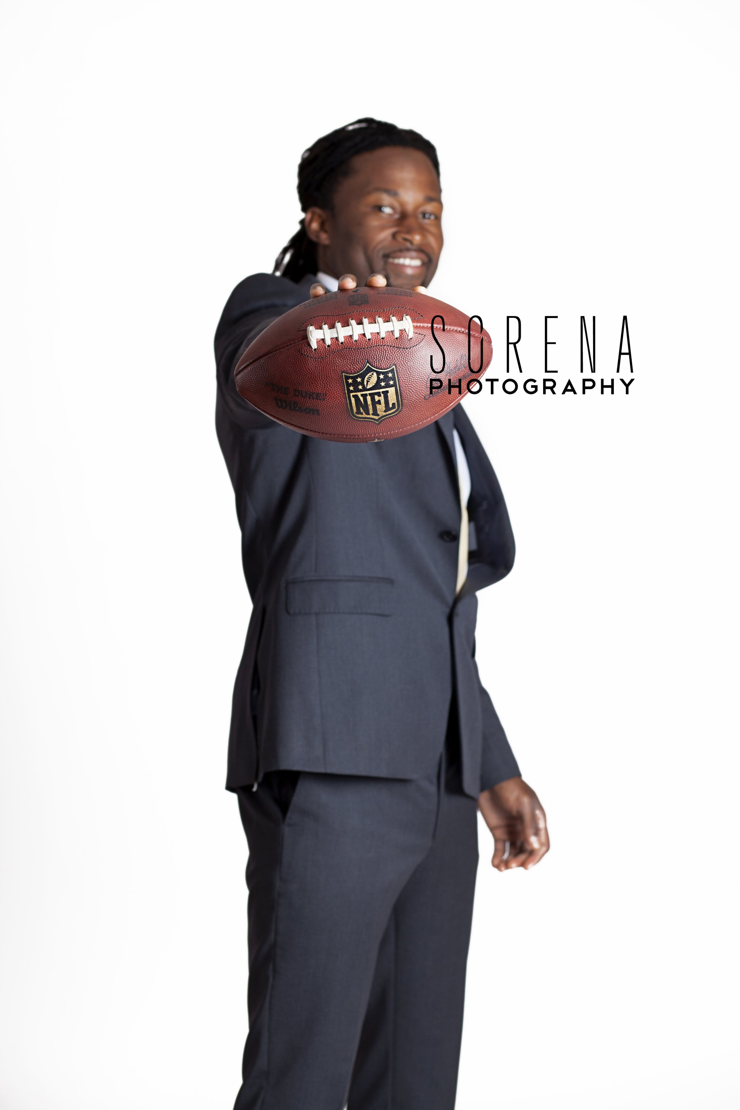 Travaris Cadet, in a sleek suit, grips a football, ready to bring his game face from the locker room to the office.