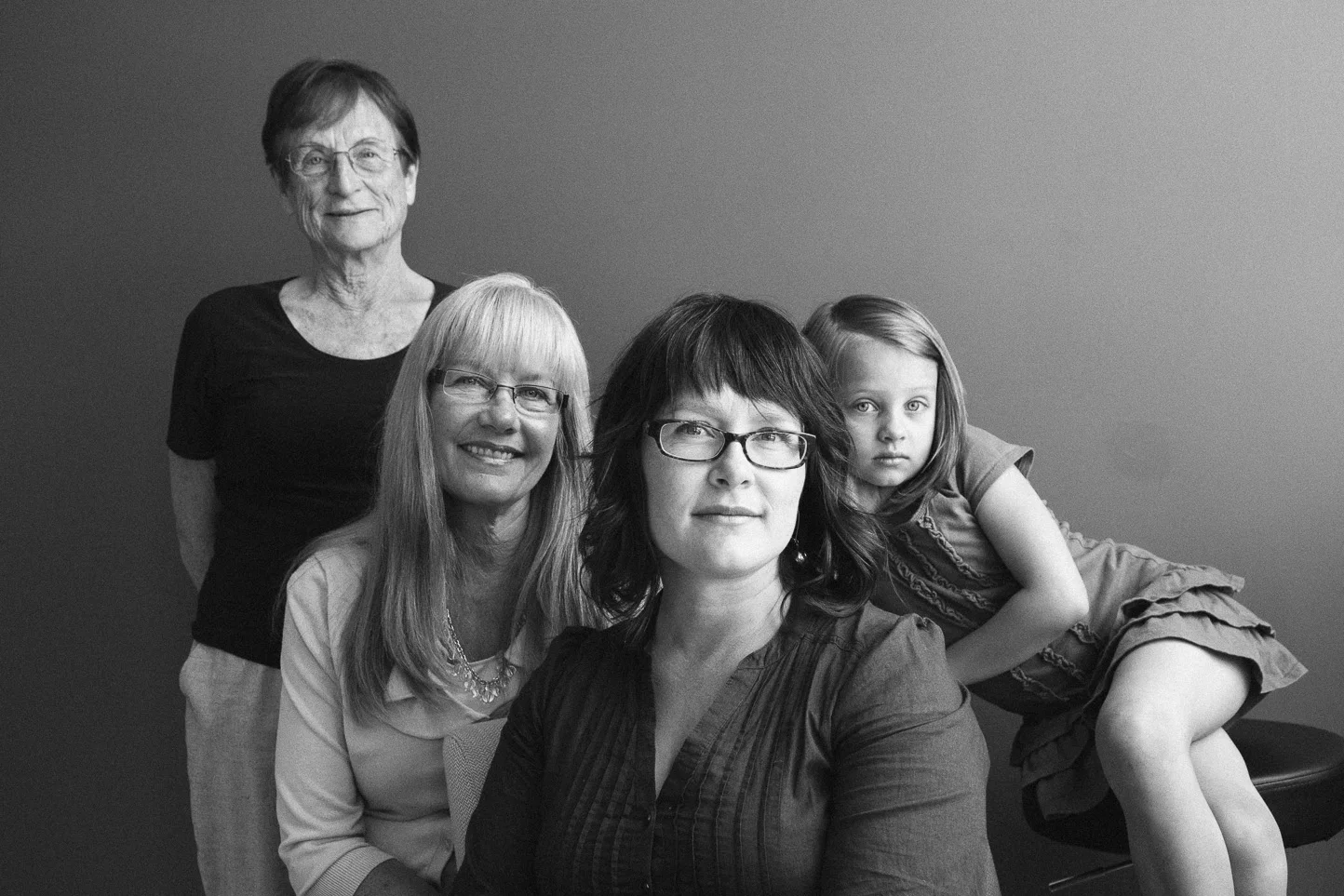 Black and white photo of four women and one girl posing together, with one woman sitting and the others standing behind her, against a plain background.
